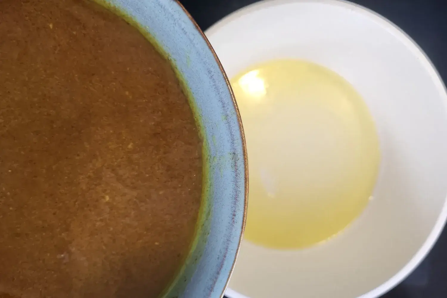 A bowl of broth above a pot with melted butter.