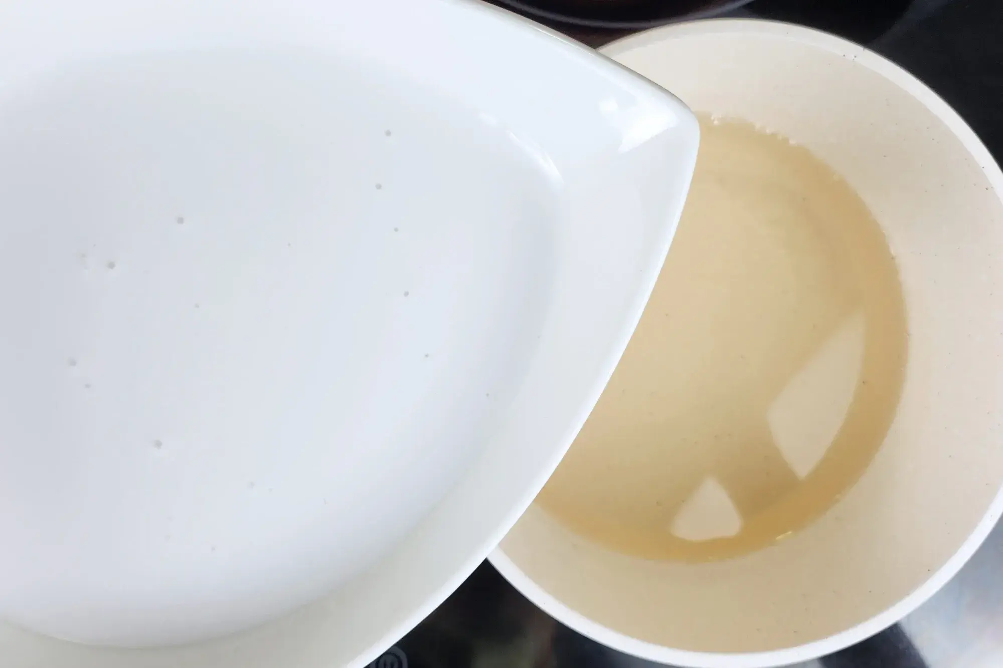 A bowl of coconut milk above a pot