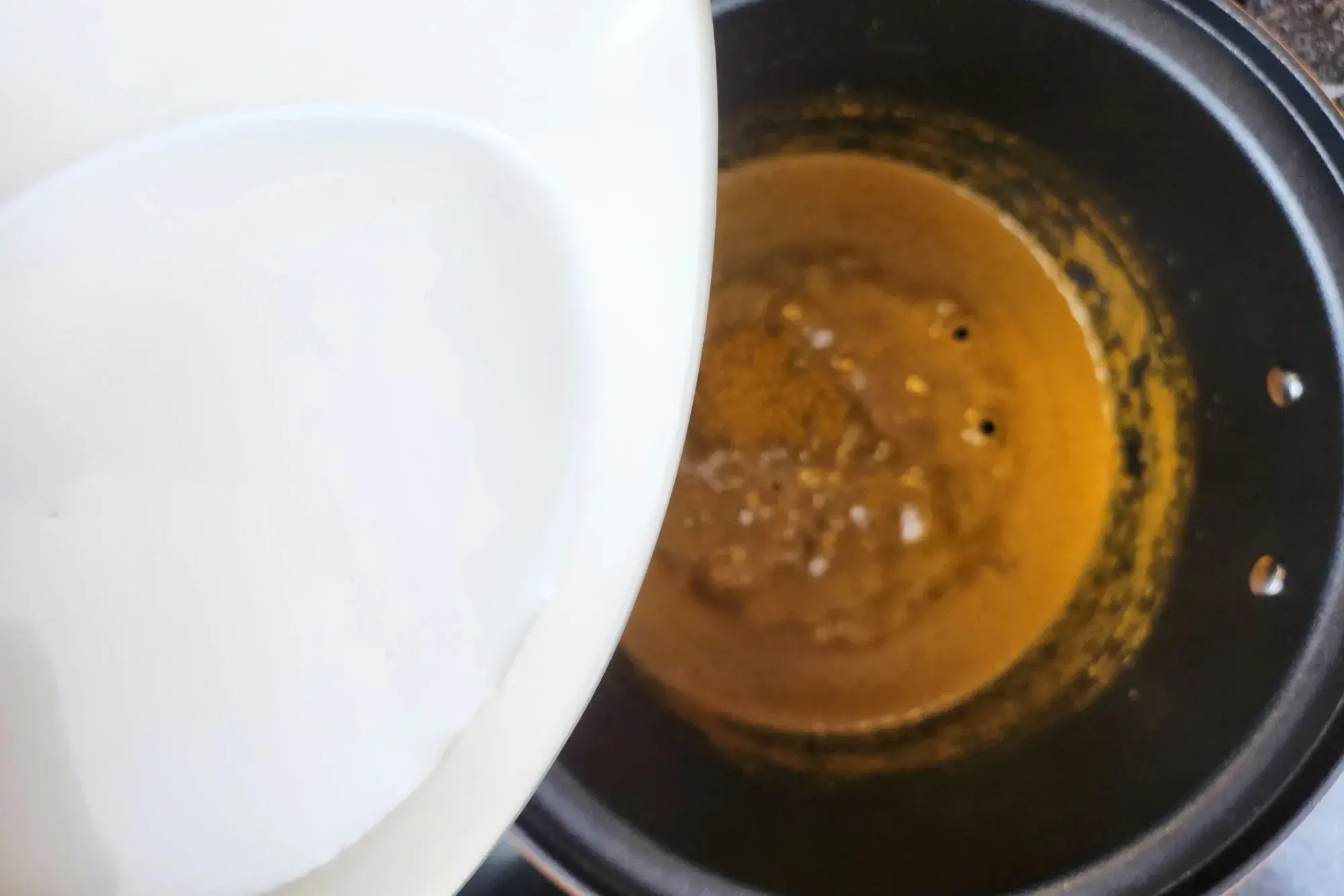 A bowl of coconut milk above the curry pot.