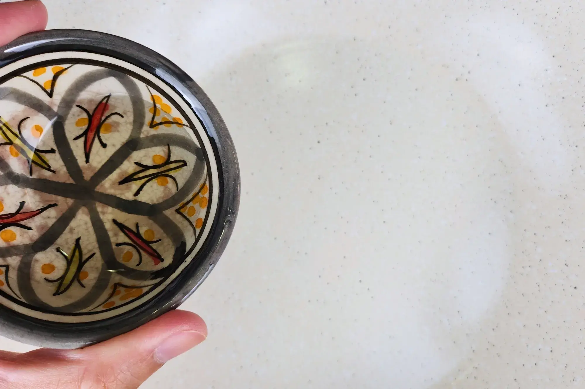 A bowl of cooking oil is above a pan