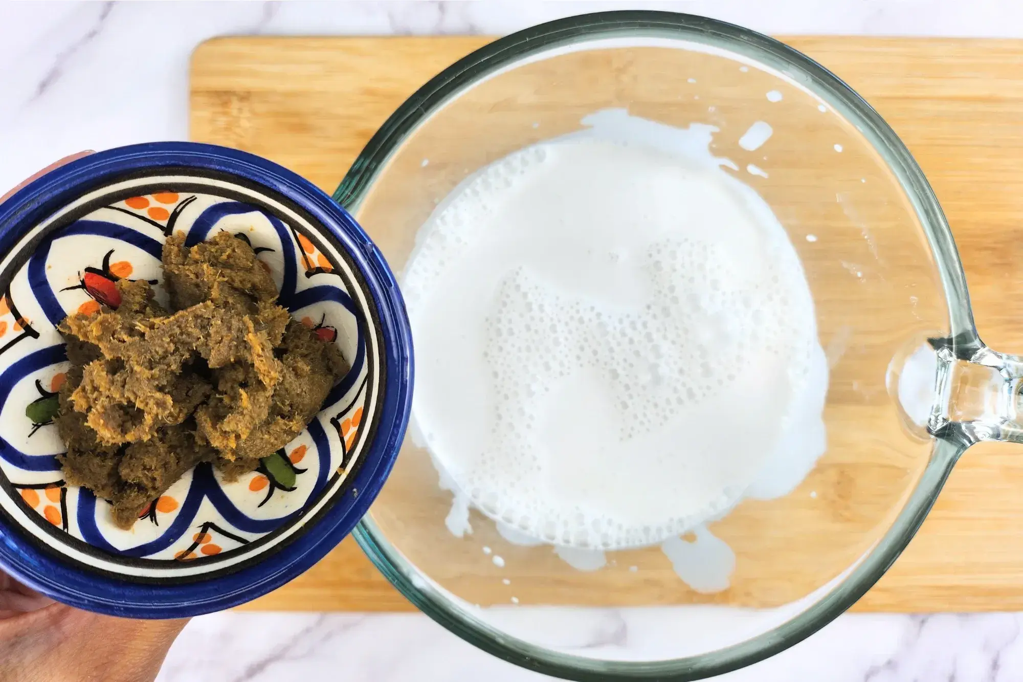 A bowl of green chili paste above a jar of coconut milk.