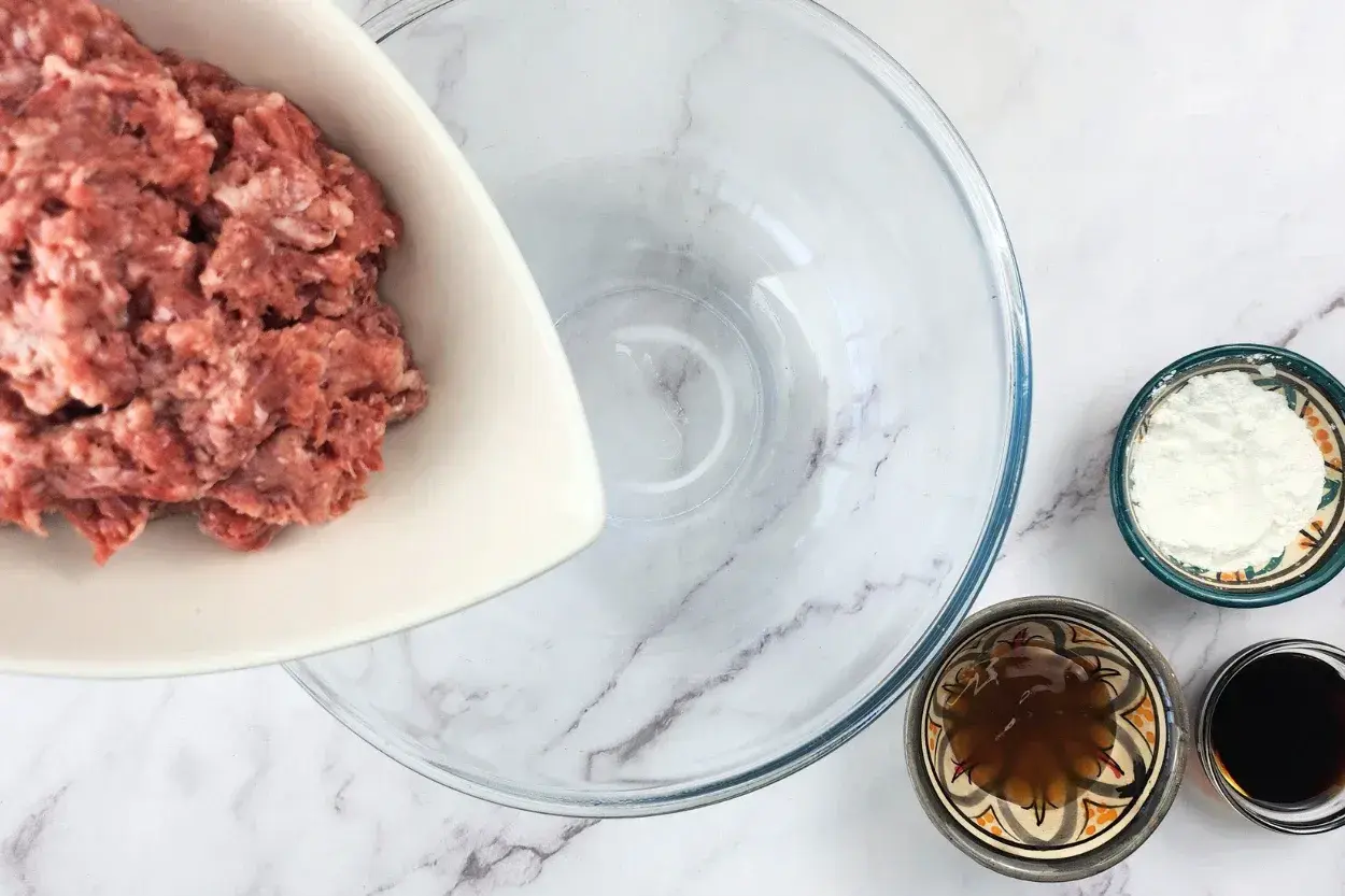 A bowl of ground beef above an empty mixing bowl.