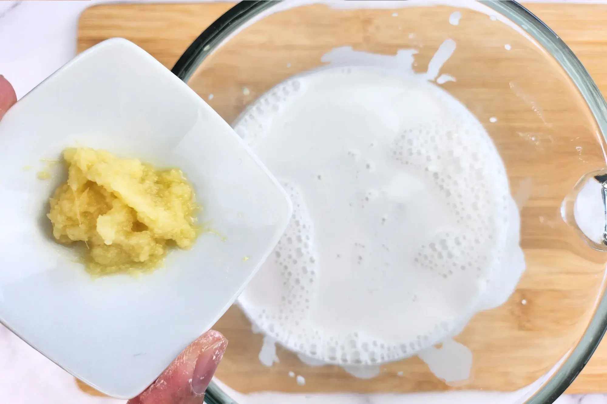 A bowl of minced garlic above a jar of coconut milk.