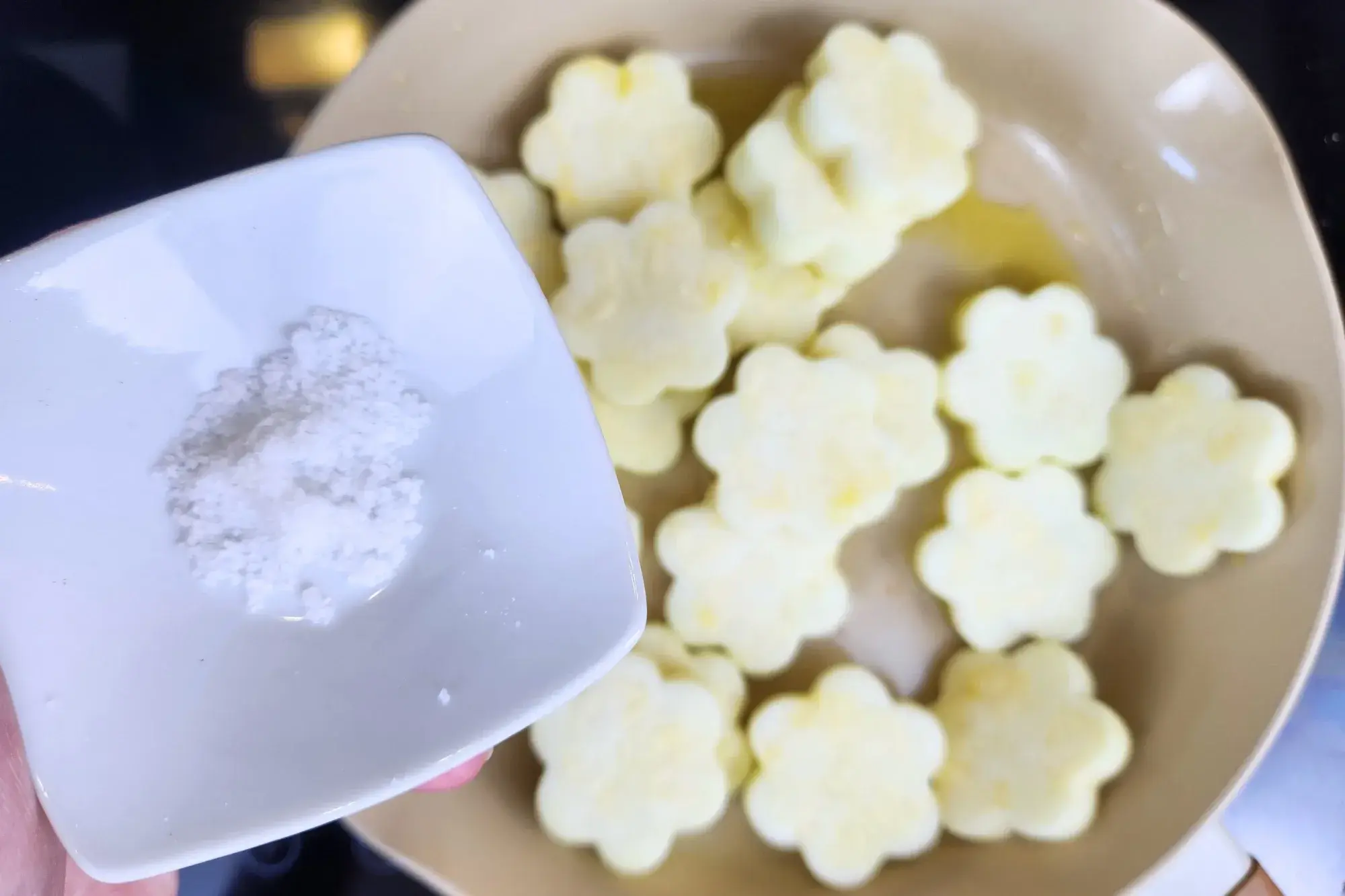 A bowl of salt is above a pan filled with center of zucchini