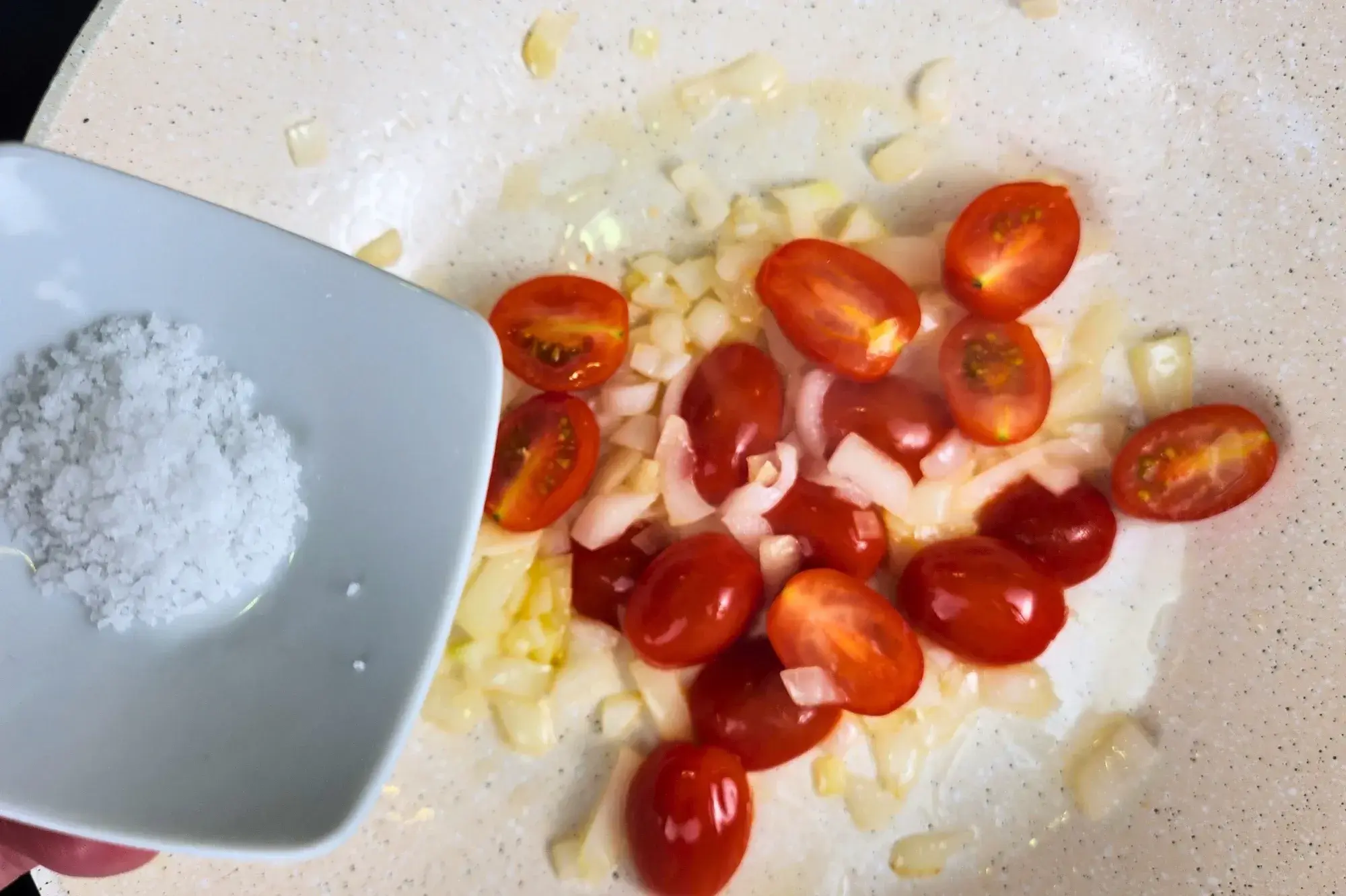 A bowl of cooking oil is above a pan