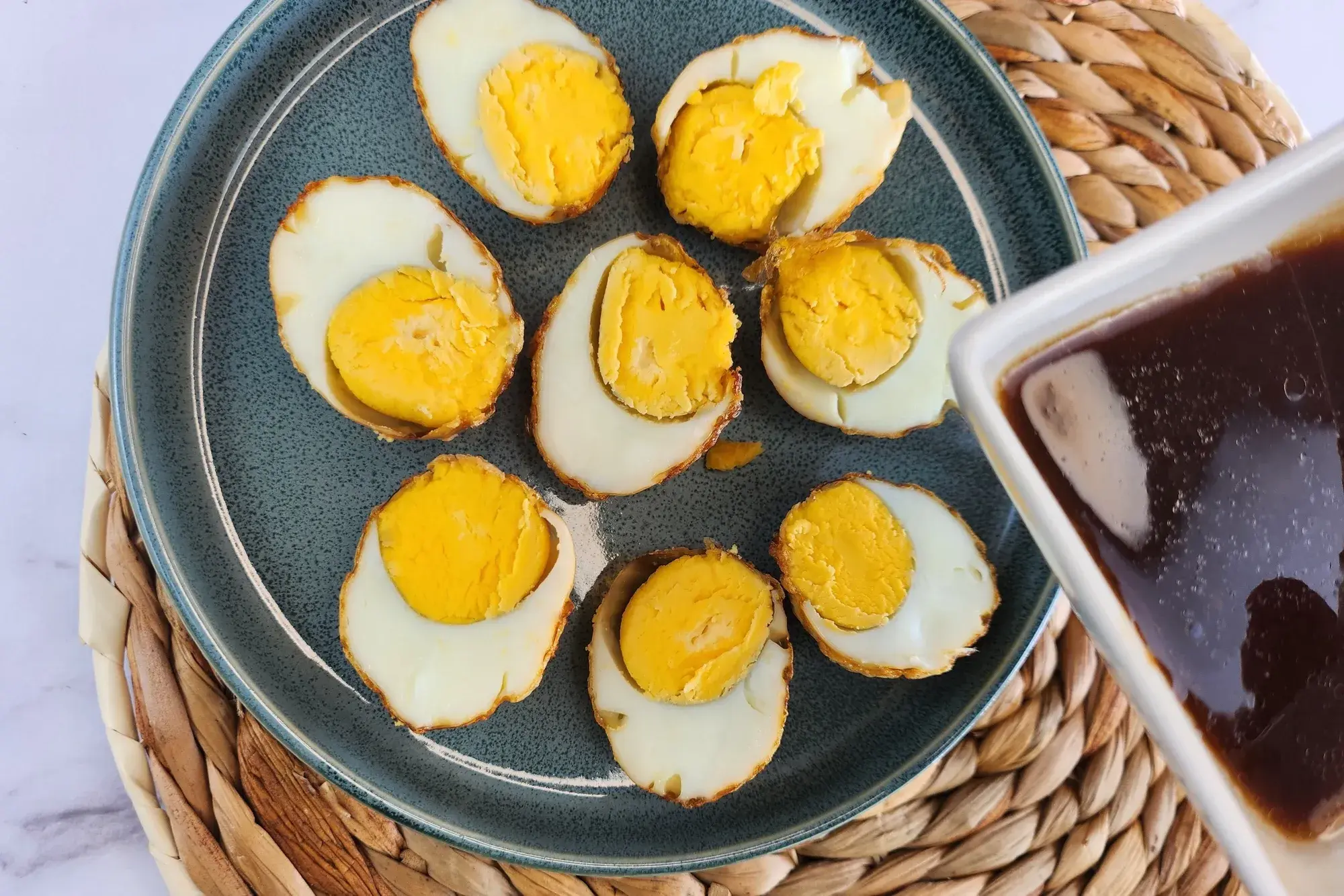 A bowl of sauce above cut eggs.
