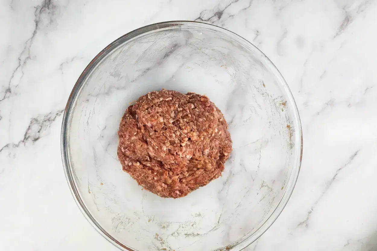 A bowl of seasoned ground beef in a mixing bowl.