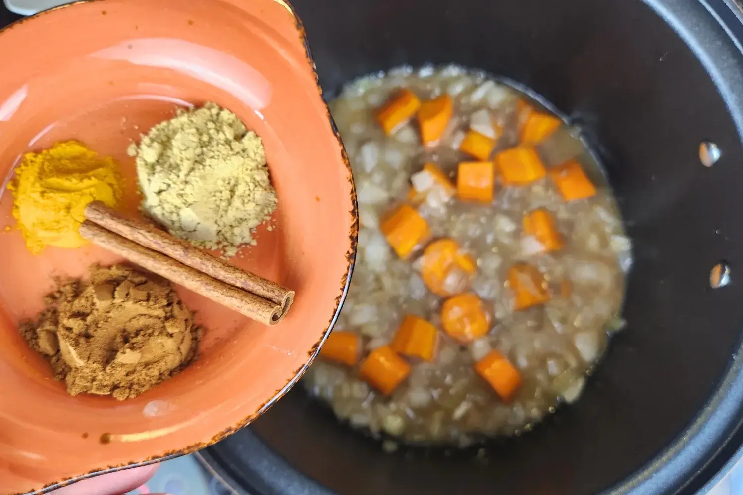 A bowl of spices above a cooking pot.