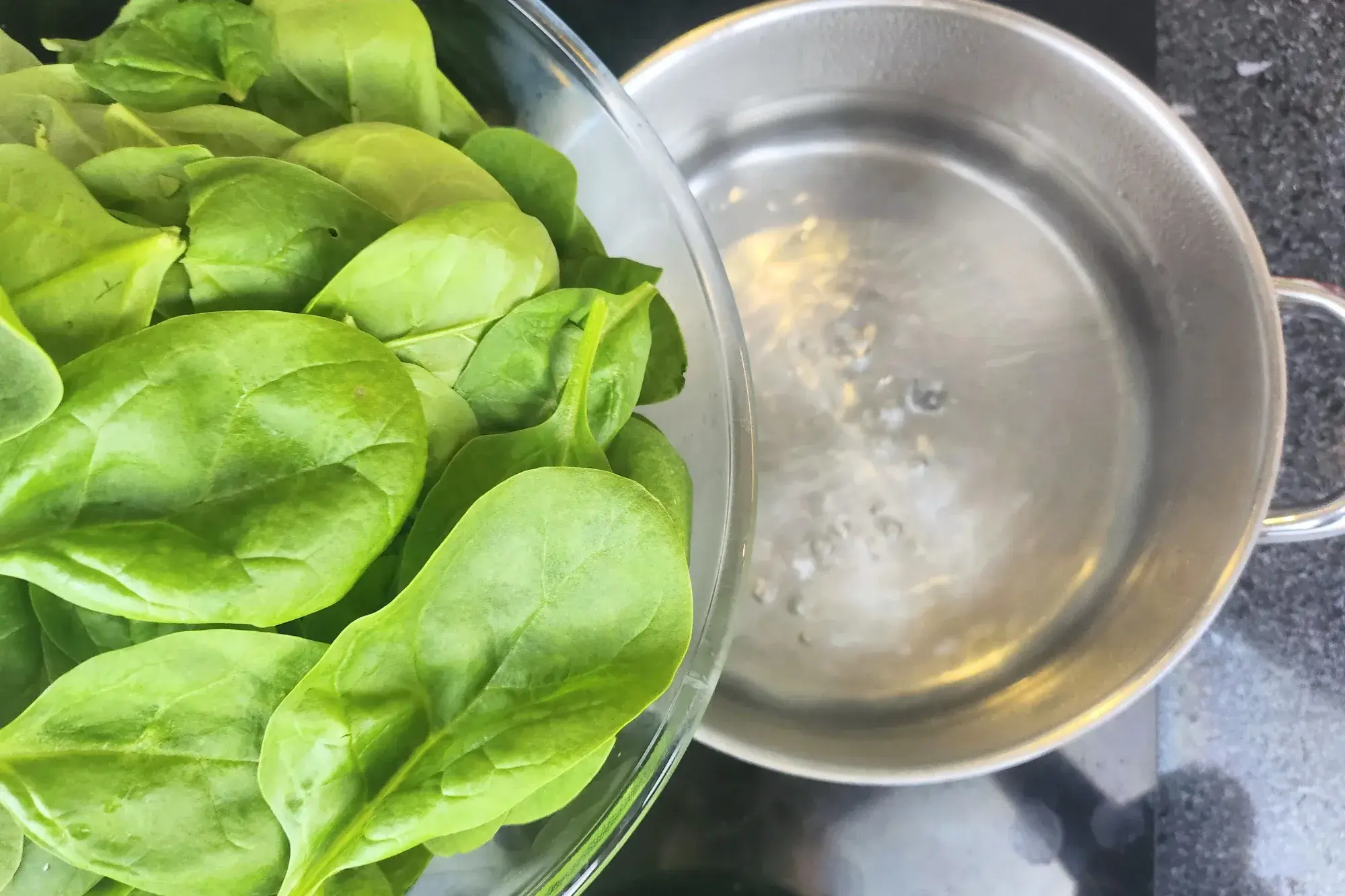 A bowl of spinach above boiling water pot