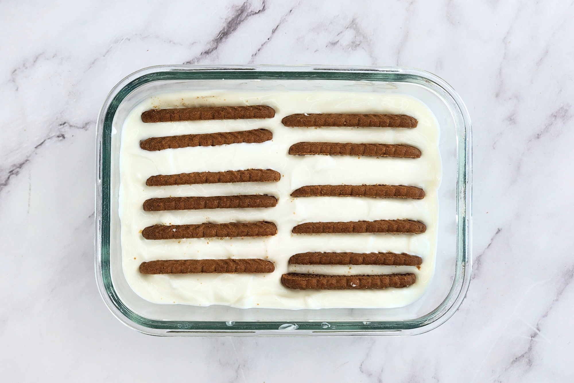 A bowl of yogurt with some cookies.