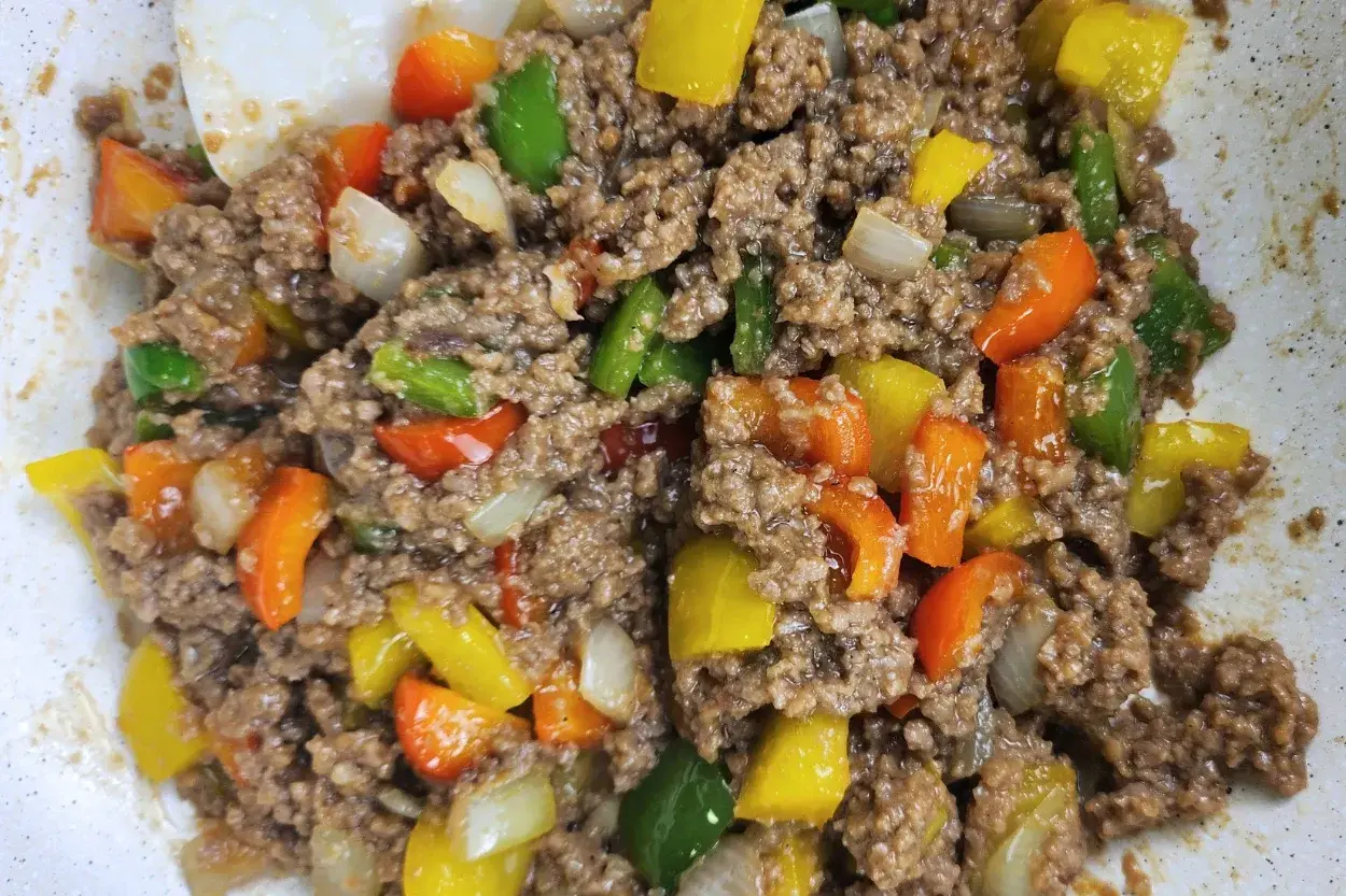 A cooked ground beef with mix bell peppers and onions in a wok.