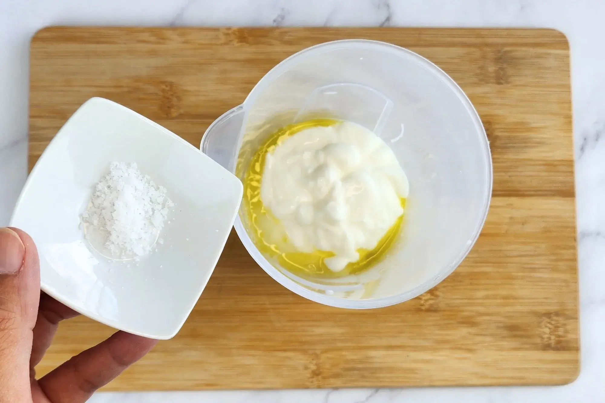 A hand is hold a bowl of salt above a jar of cooked center of zucchini. 