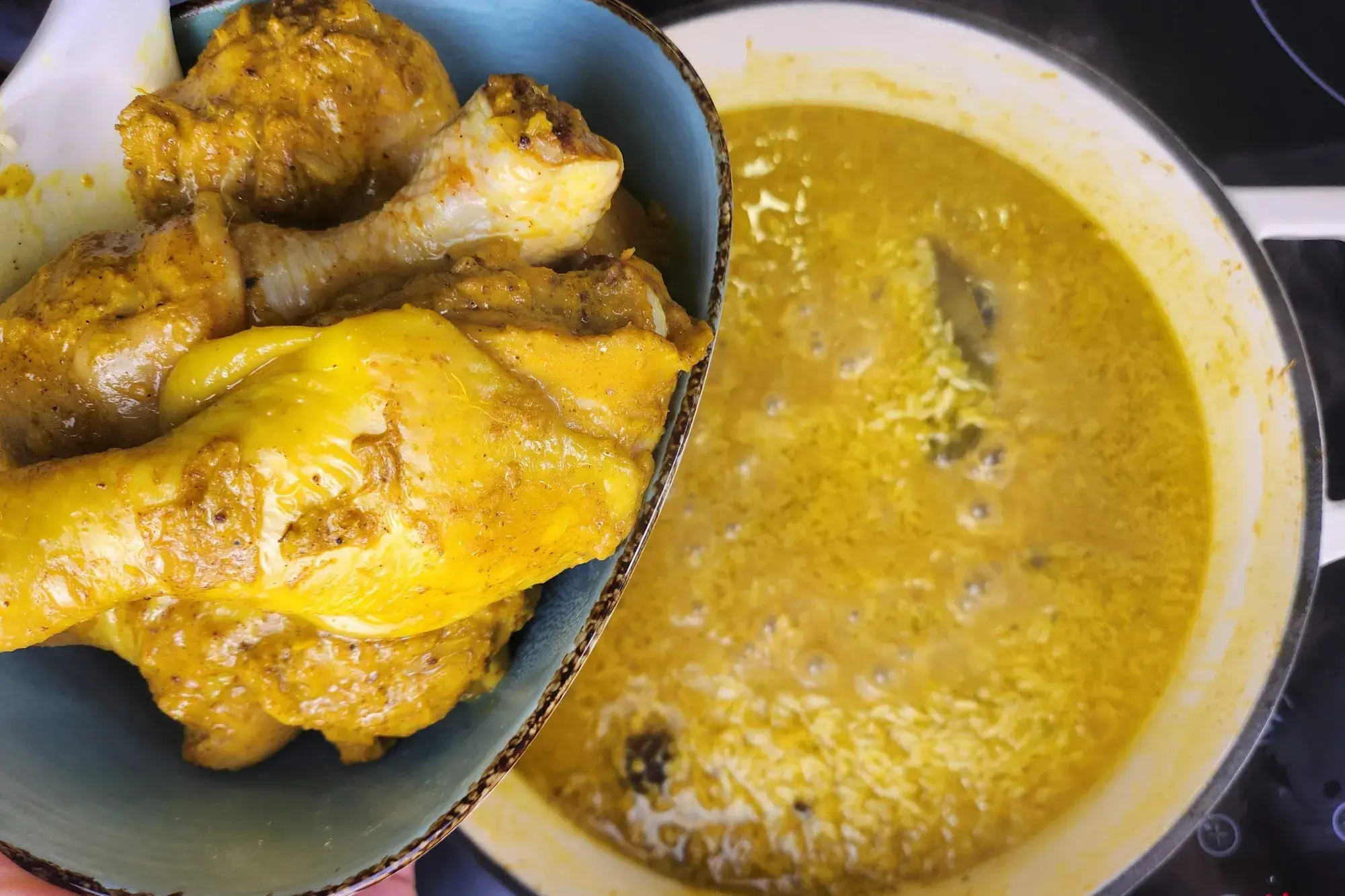 A hand is holding a bowl of cooked chicken above a pot with rice.