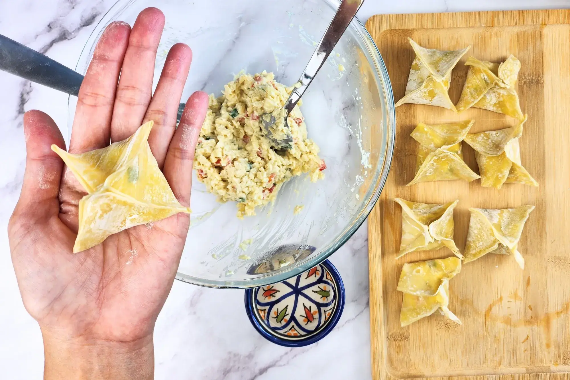 A hand is holding a finished folding wonton.