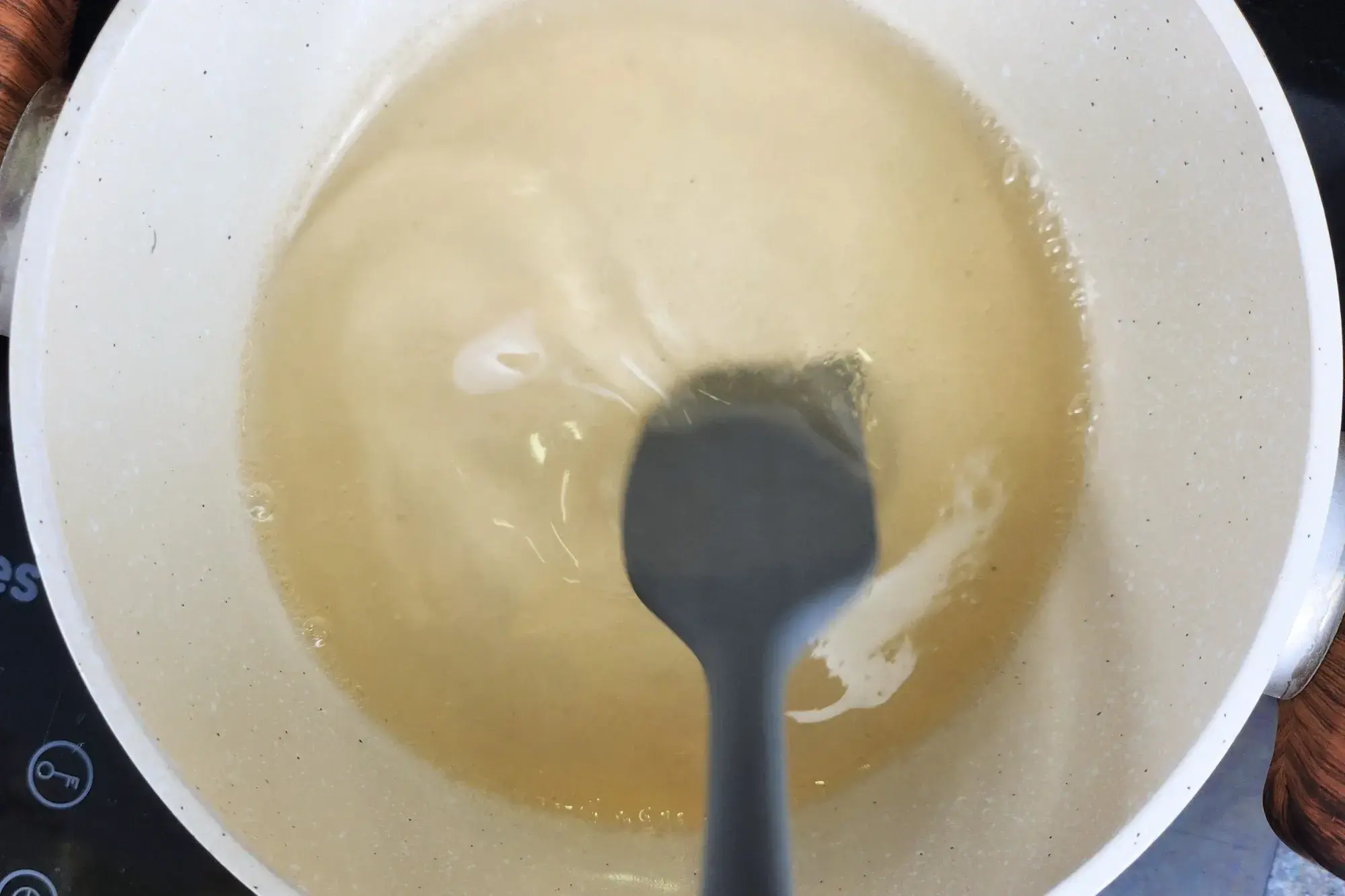 A hand is holding a spatula stir the pot of boiling water