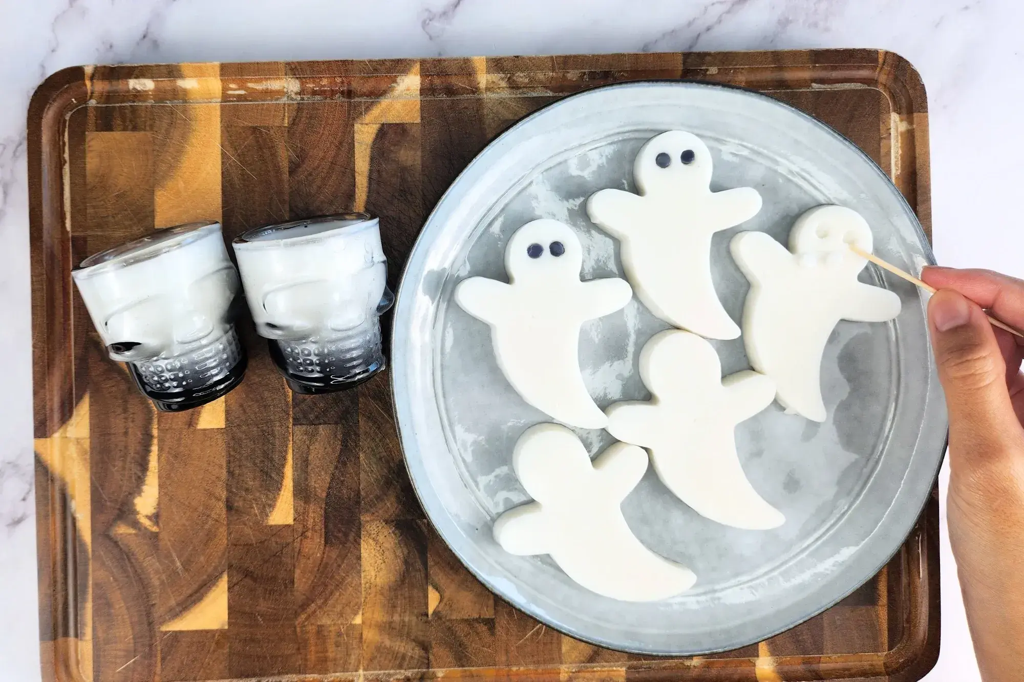 A hand is holding a toothpick to make holes on white ghost jelly