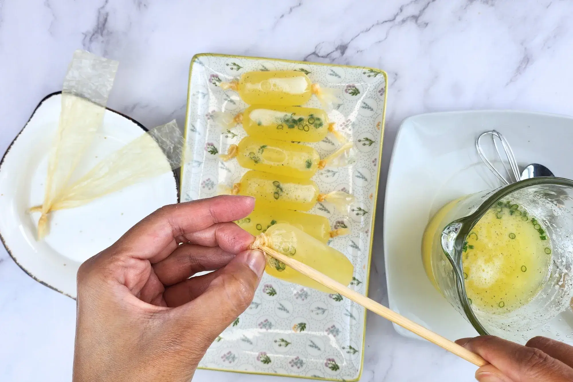 A hand using a chopstick with sausage