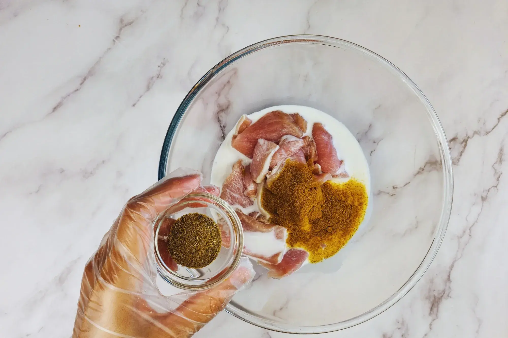 A mixing bowl and a hand holding of bowl of cumin powder