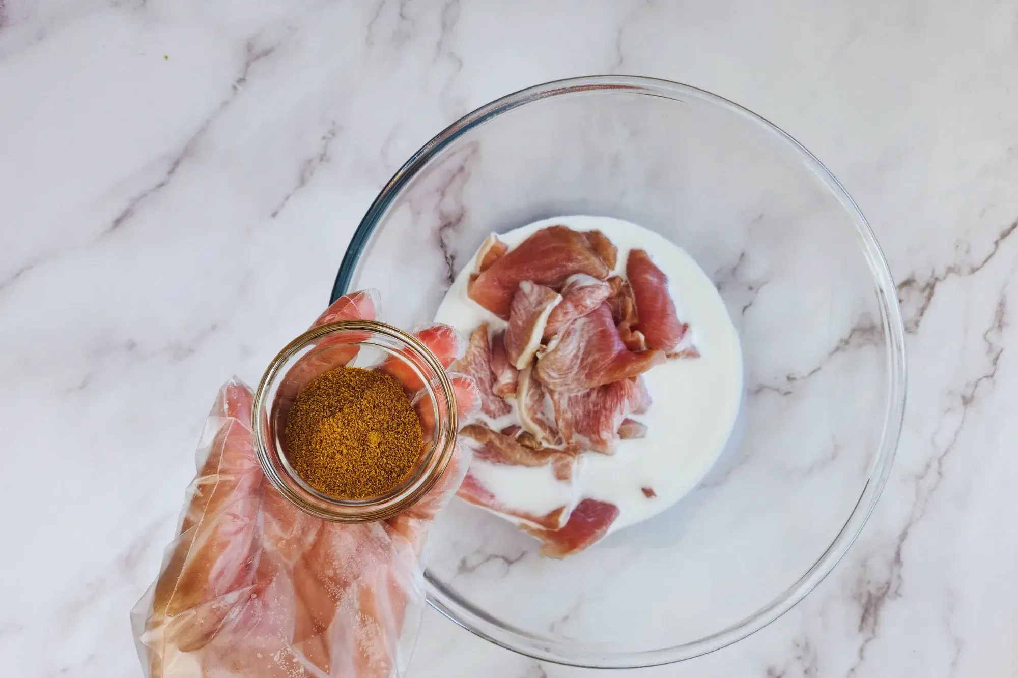 A mixing bowl and a hand holding of bowl of curry powder
