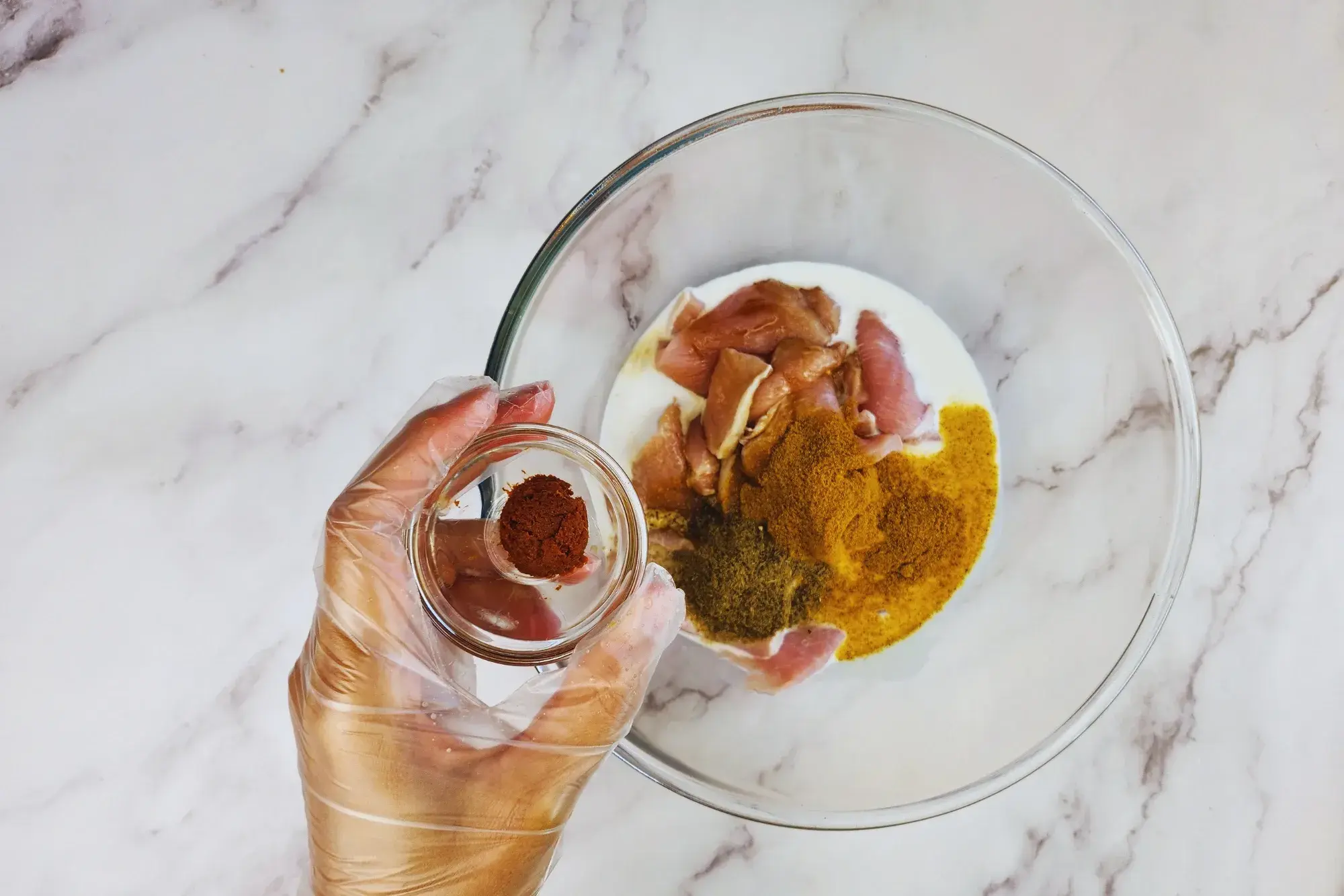 A mixing bowl and a hand holding of bowl of red curry paste