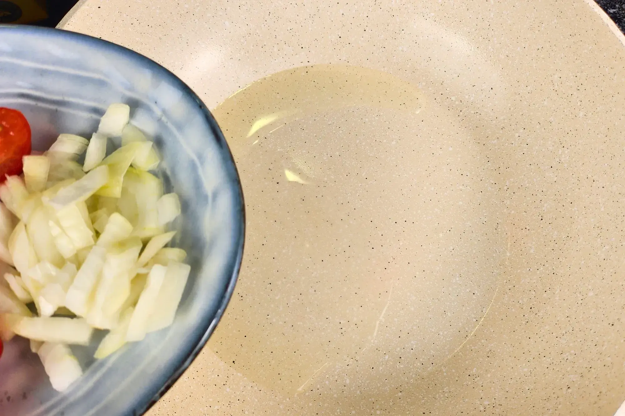 A bowl of cooking oil is above a pan