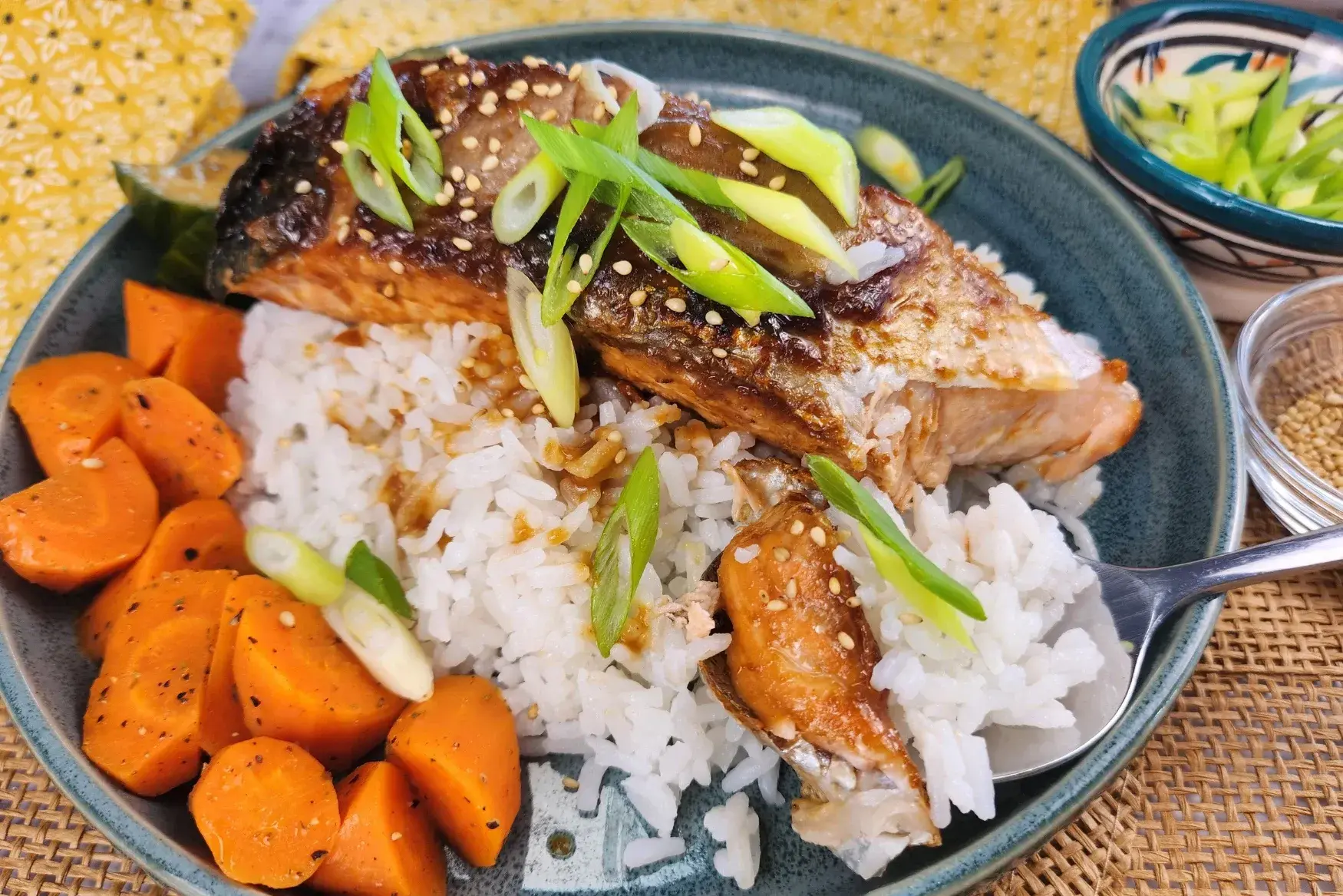 A plate of Miso Glazed Salmon above cooked rice with a spoon bite of it.