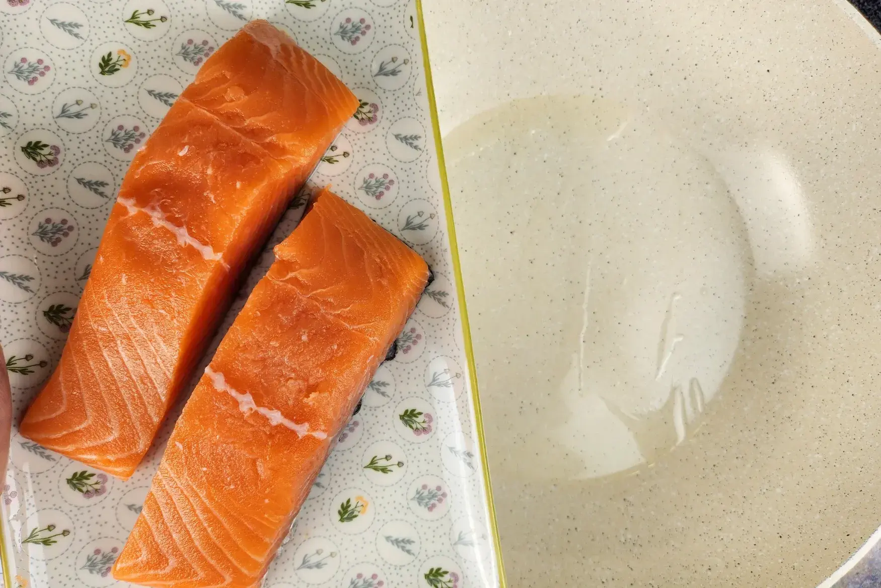 A plate of salmon fillets above a wok