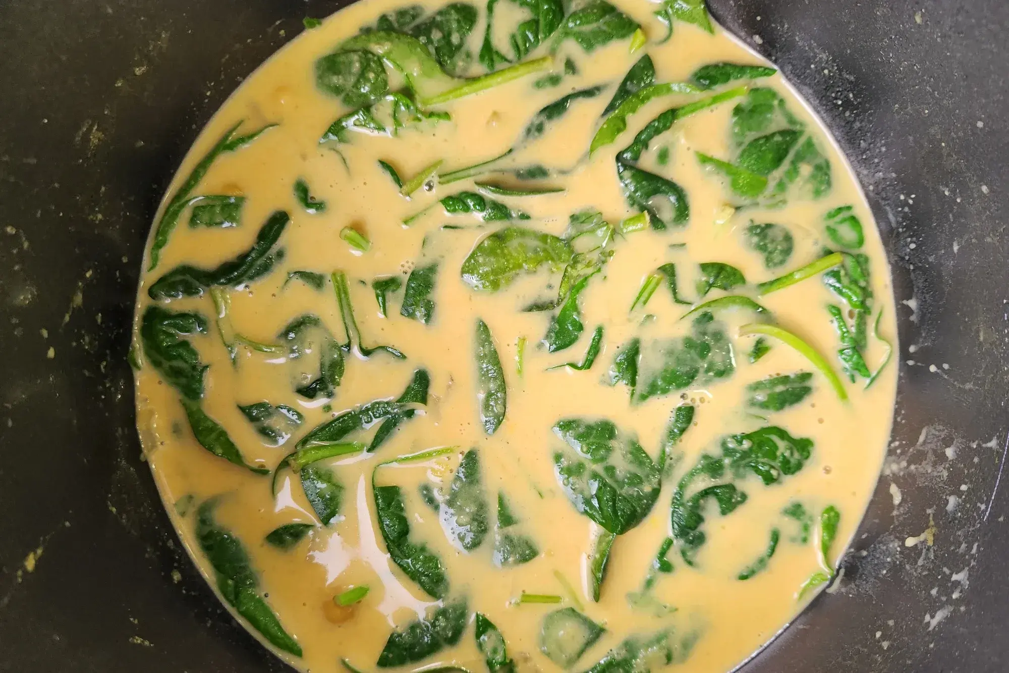 A pot with baby spinach in creamy soup