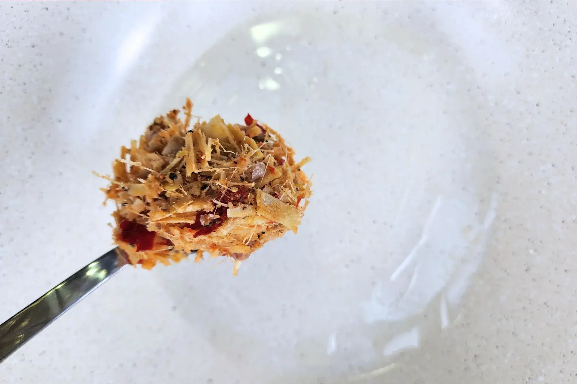 A spoonful of lemon grass chili paste is above a wok