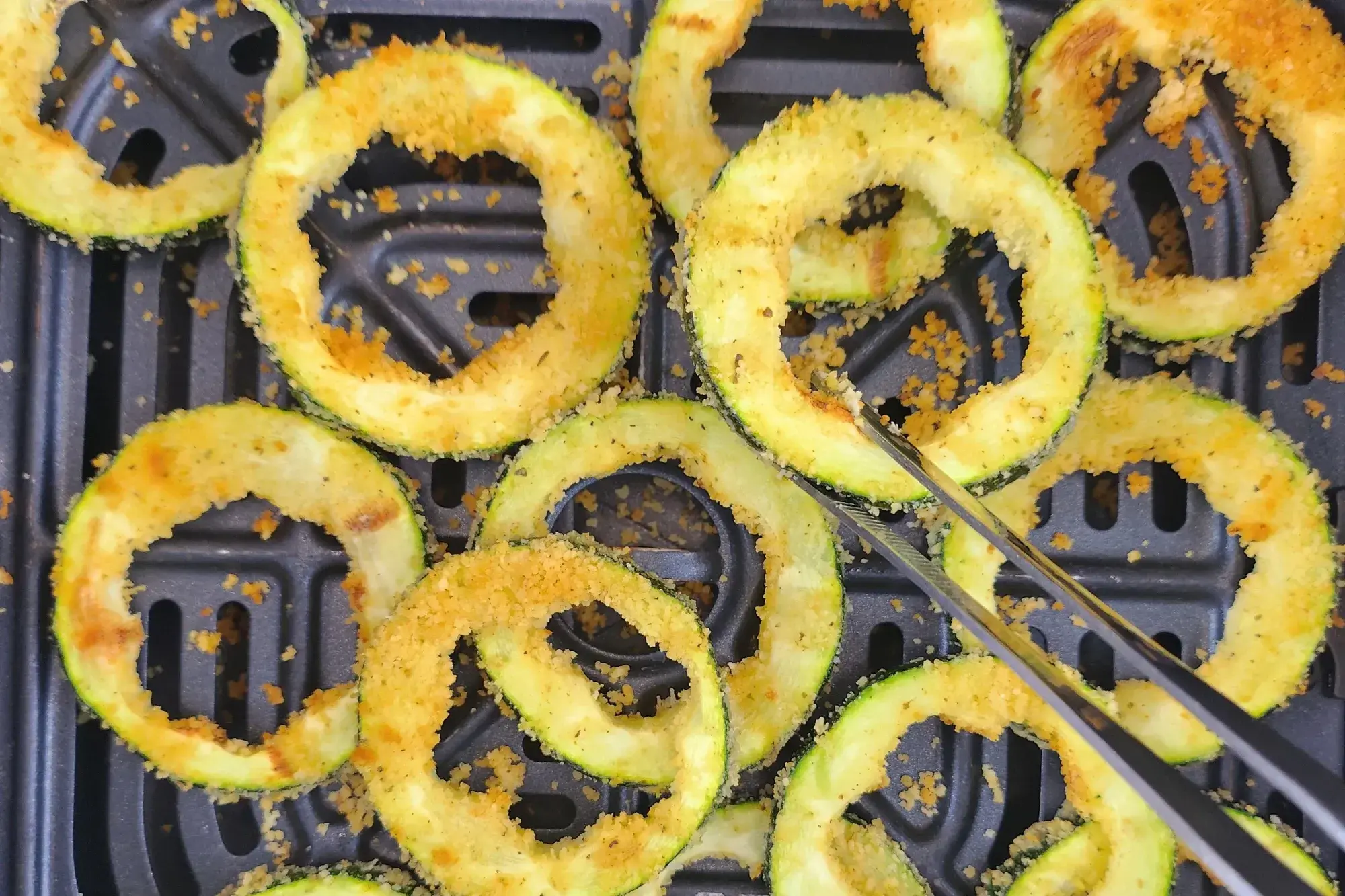 A tong is holding a zucchini ring