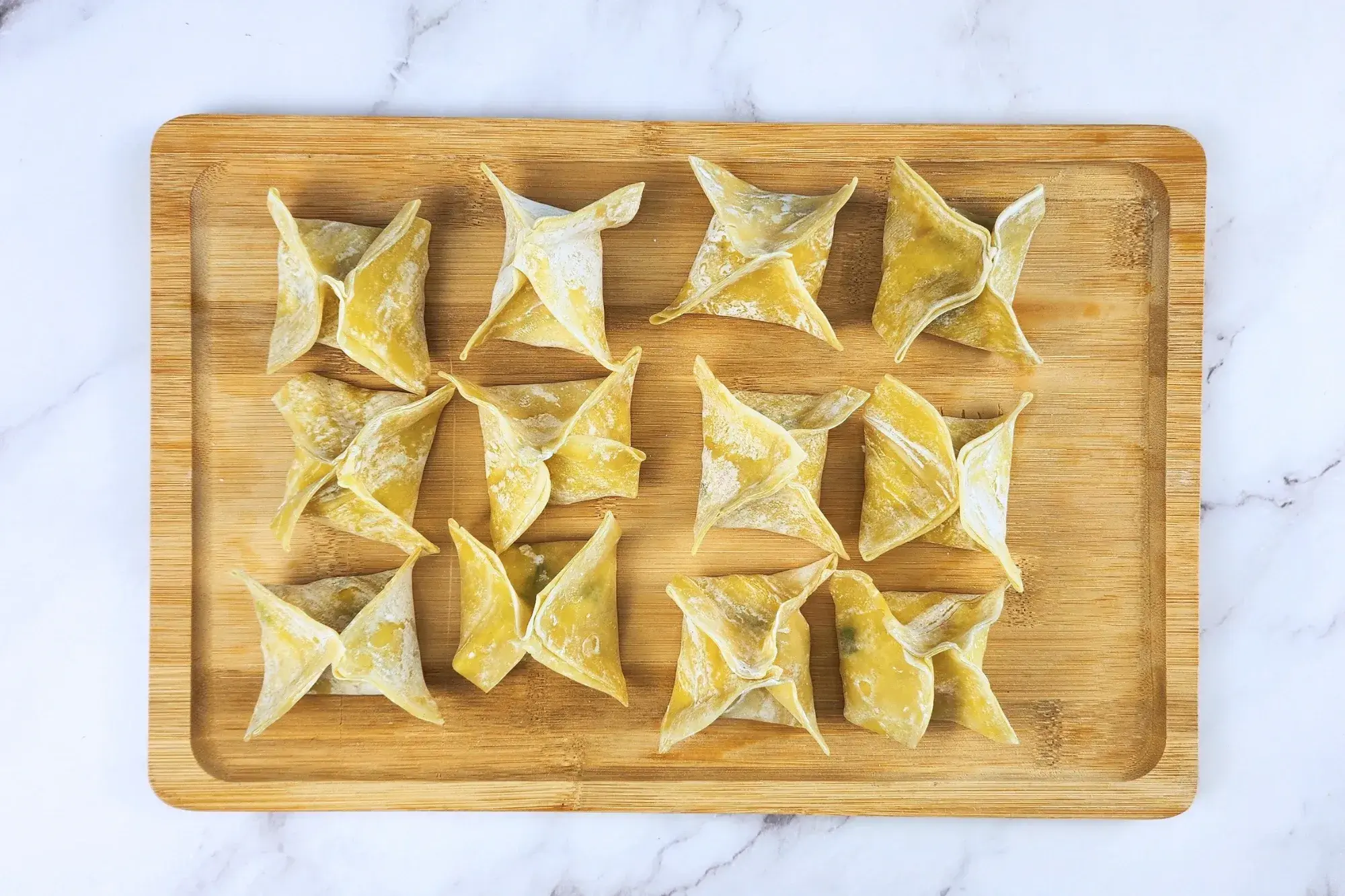 A wooden tray with uncooked vegan crab rangoon.