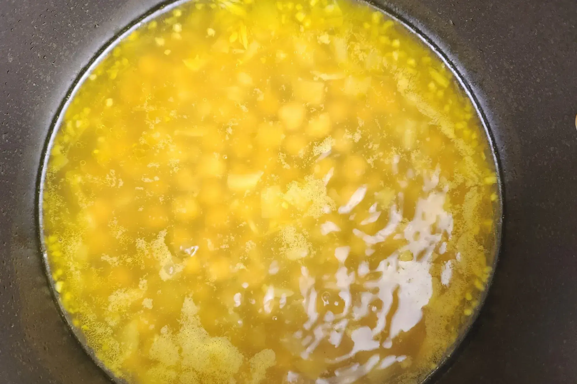 A yellow soup with chickpeas in a pot