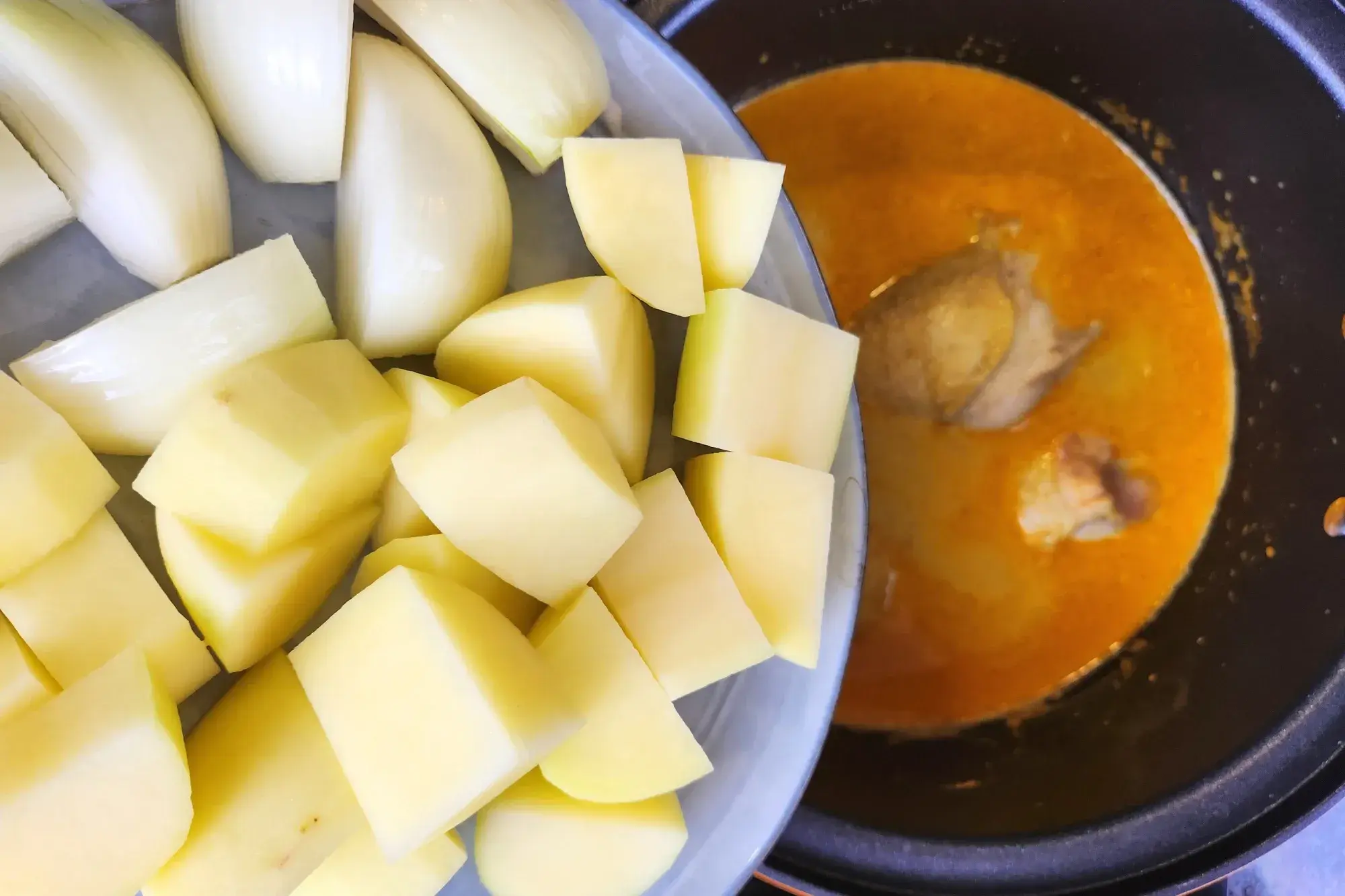 Adding chopped potatoed and chopped onion to curry pot