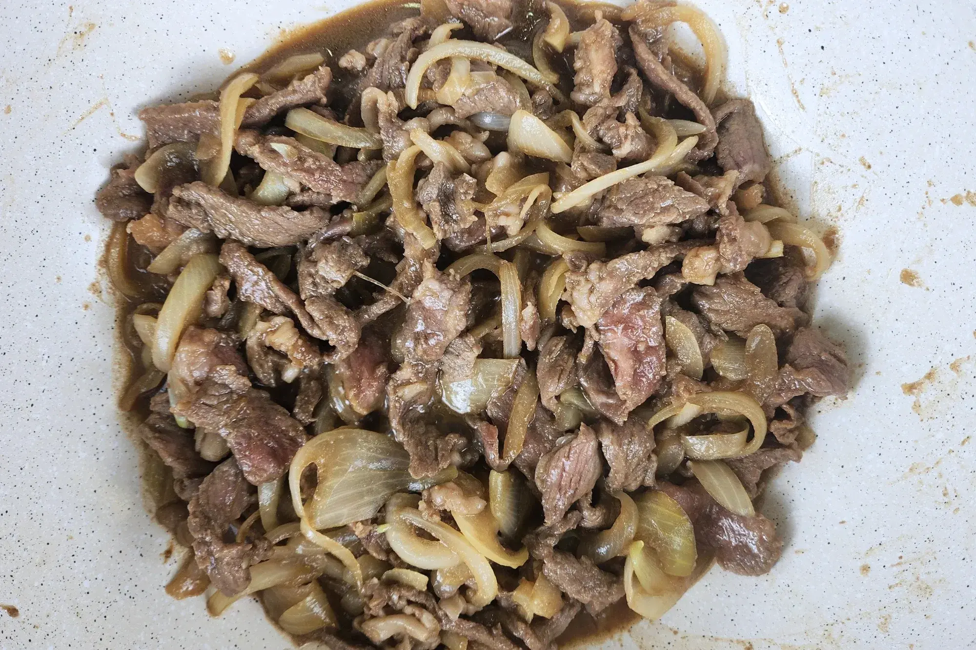 Cooked beef and onion in a wok.