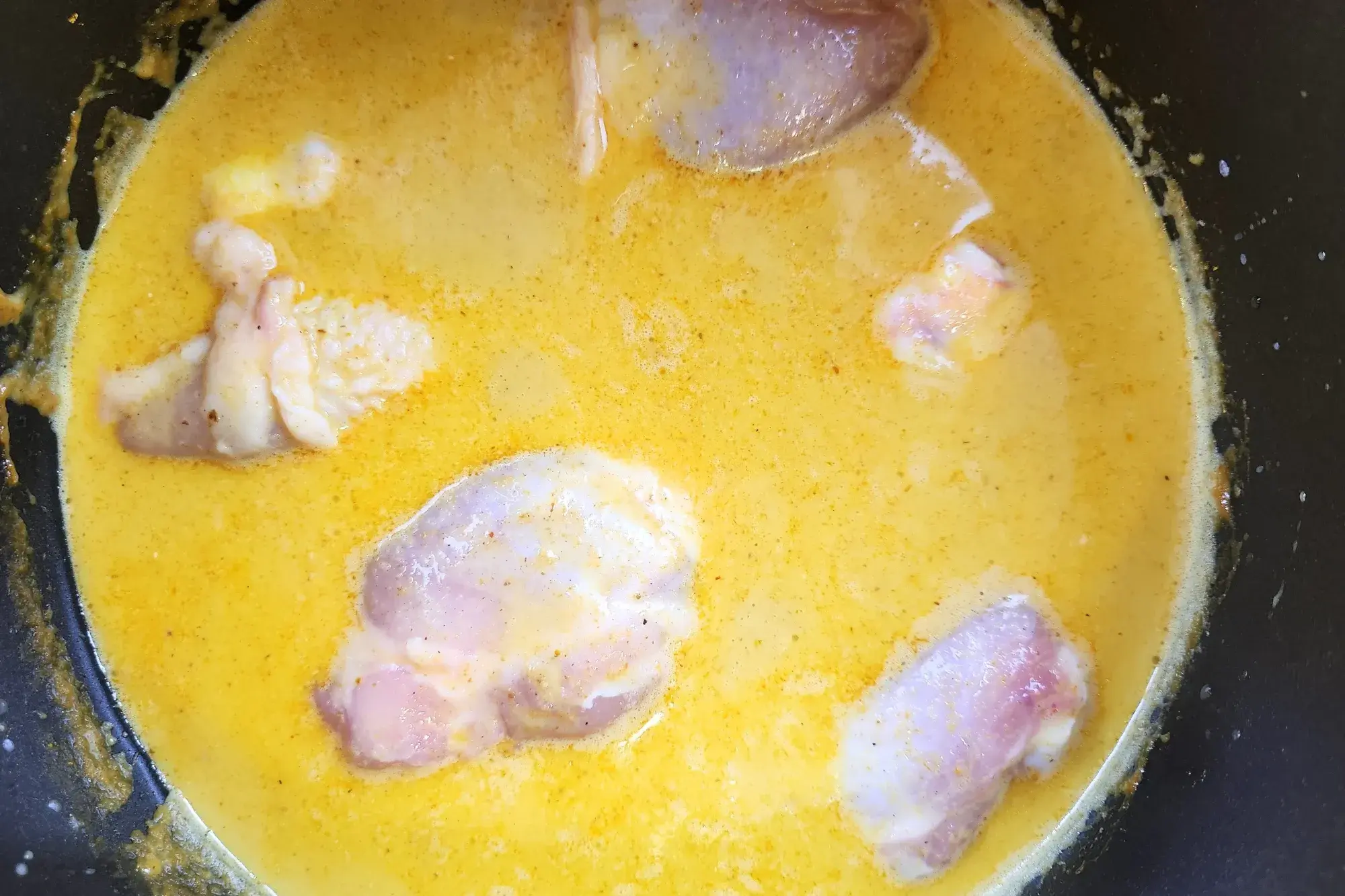 Cooking chicken in curry pot.