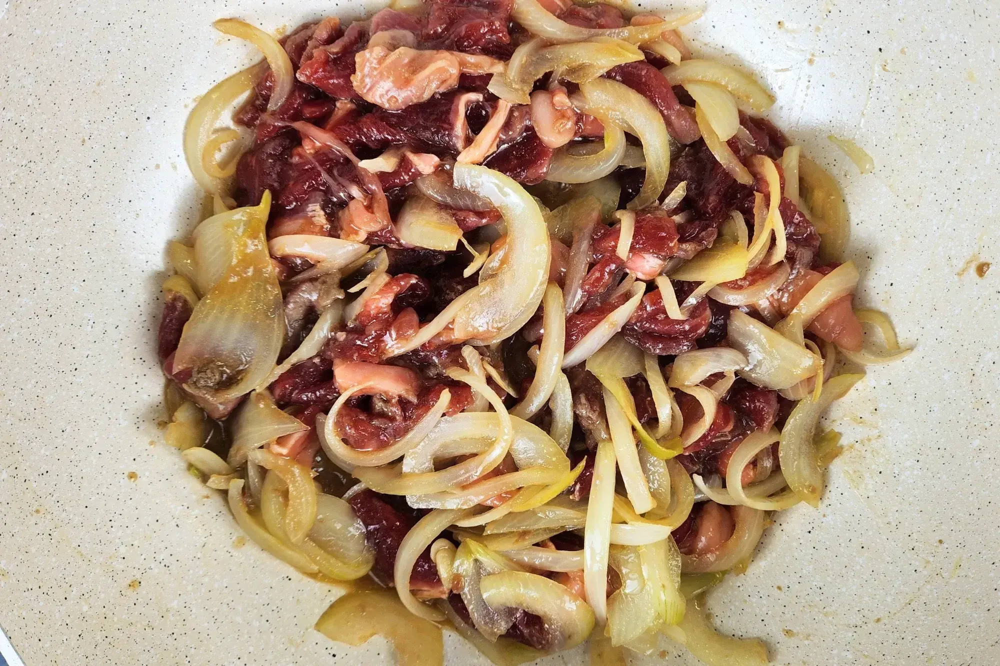 Cooking raw beef with onion in a wok.