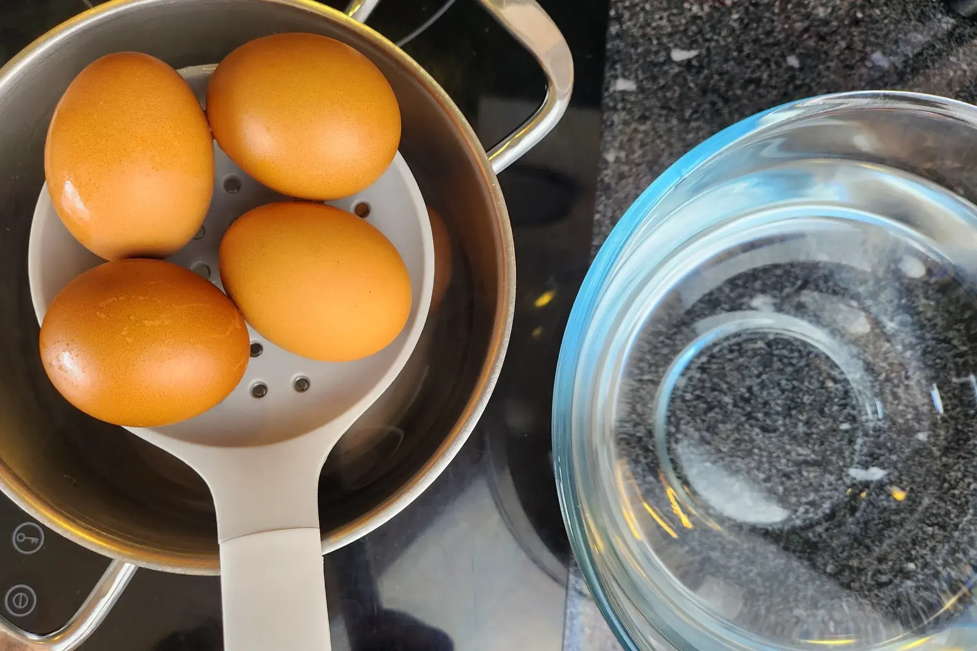 Draining 4 eggs and a bowl of cold water