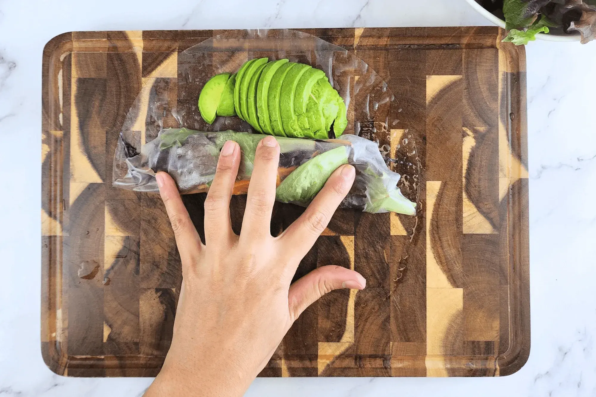 Fold the bottom of the rice paper over the filling with avocado