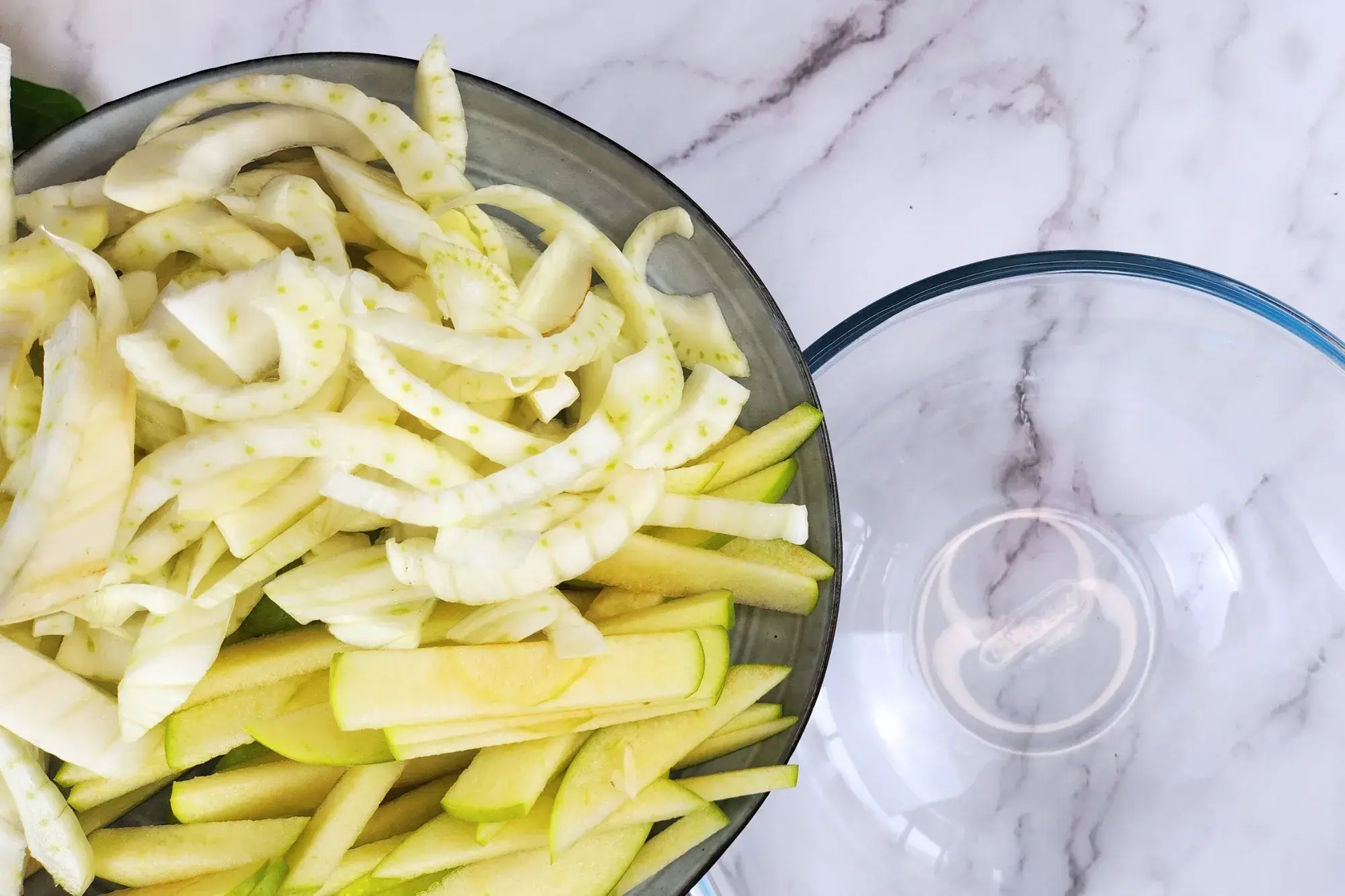 In a large mixing bowl, combine the sliced fennel and green apple
