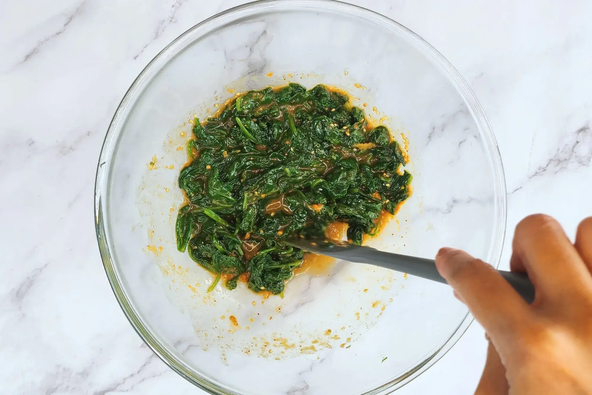 Mixing spinach with salad dressing in amixing bowl