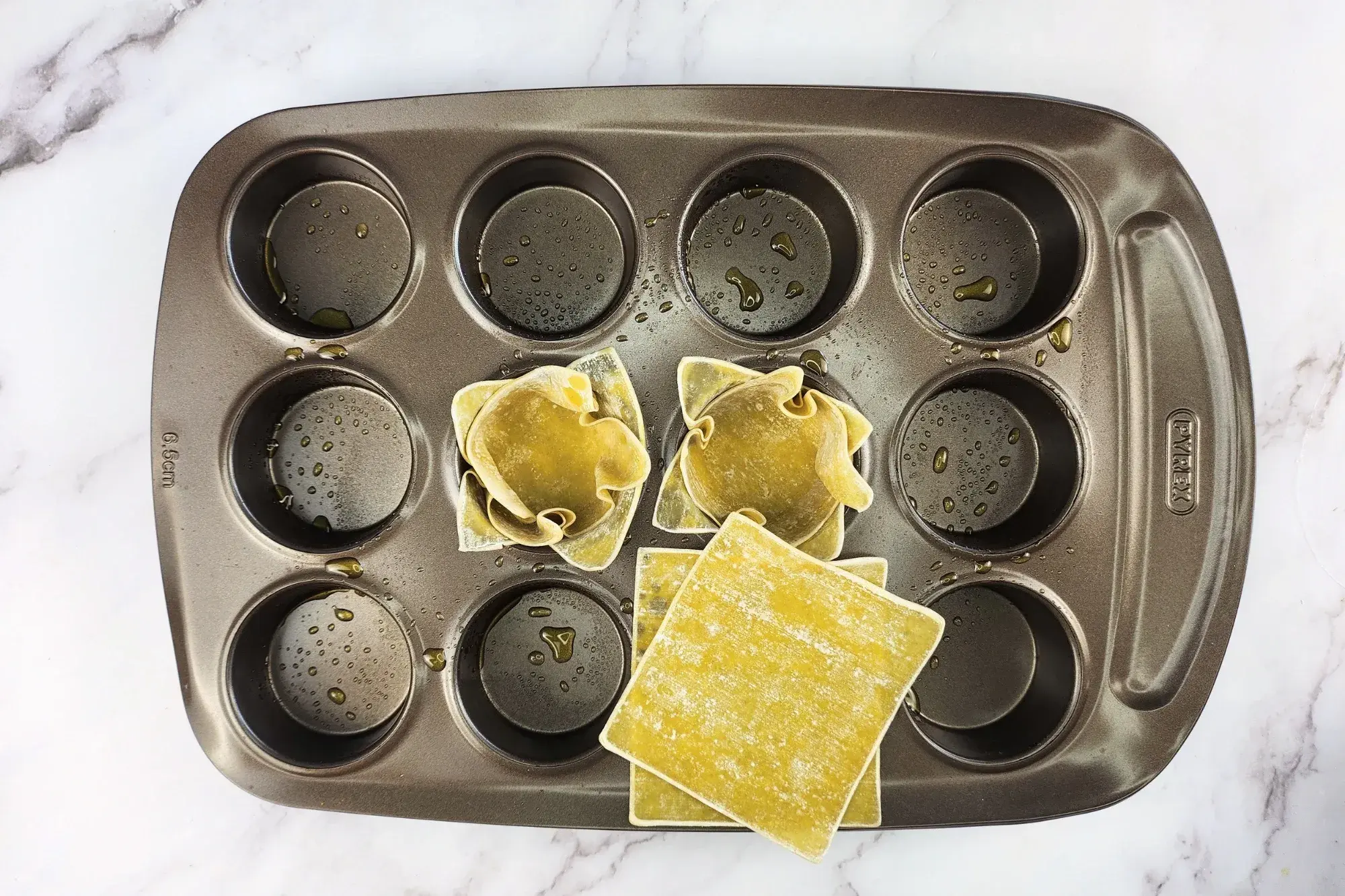 Placed wonton wrappers into muffin tray.