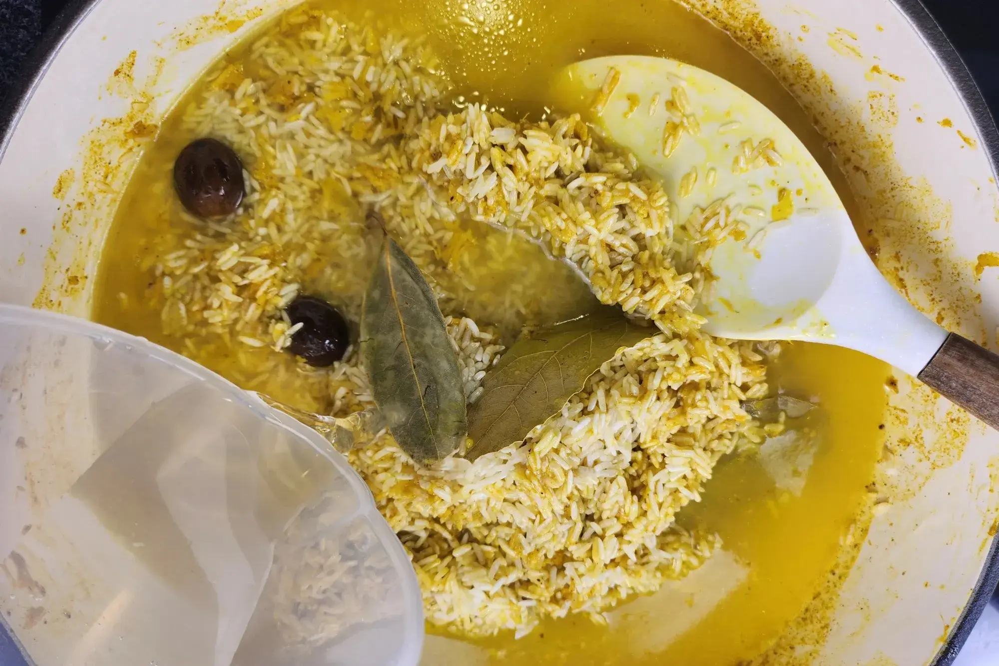 Poring water into a pot with rice and herbs.