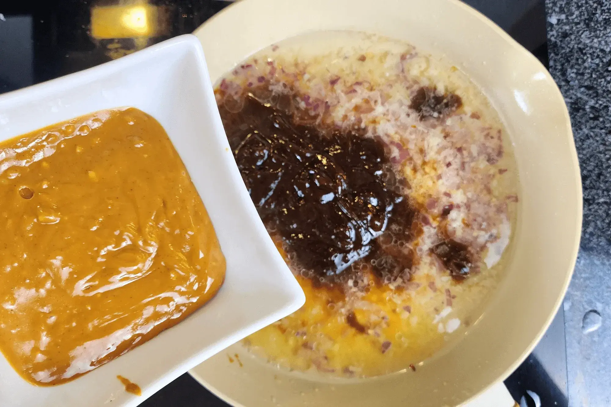 a hand holding a bowl of peanut butter with the sauce pan