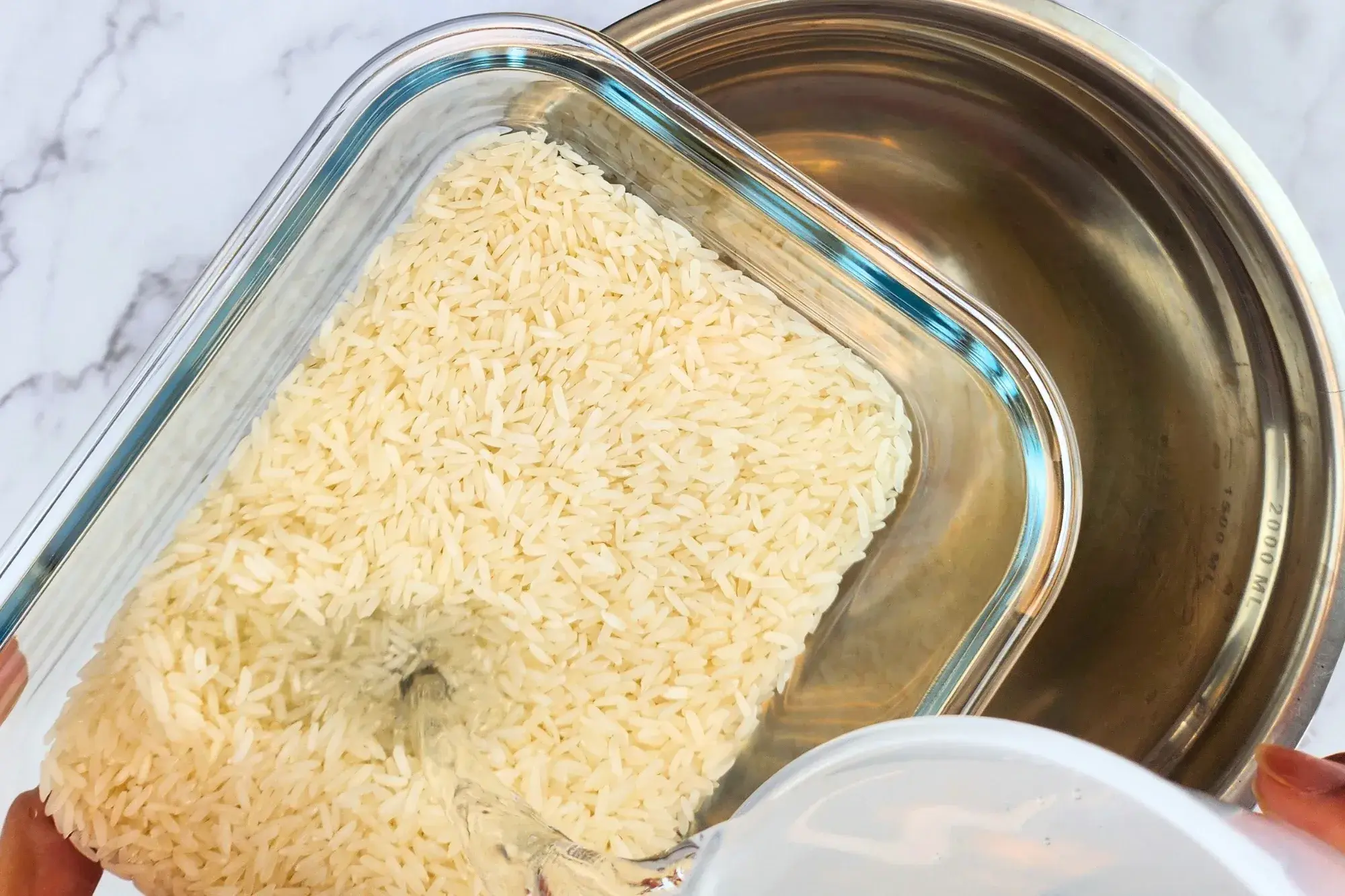 Pouring water into a container with jasmine rice above a big bowl