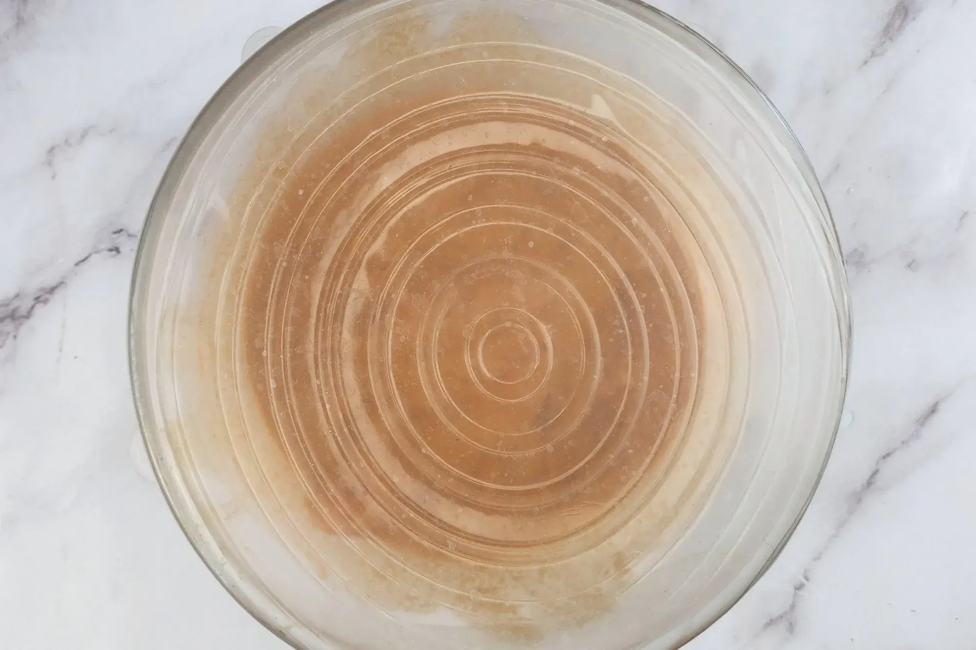 A hand is holding chicken breast covered with marinating sauce