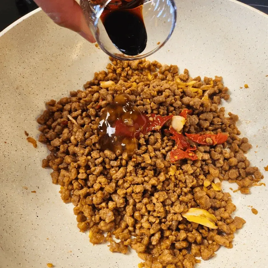 Adding black soy sauce to the pan