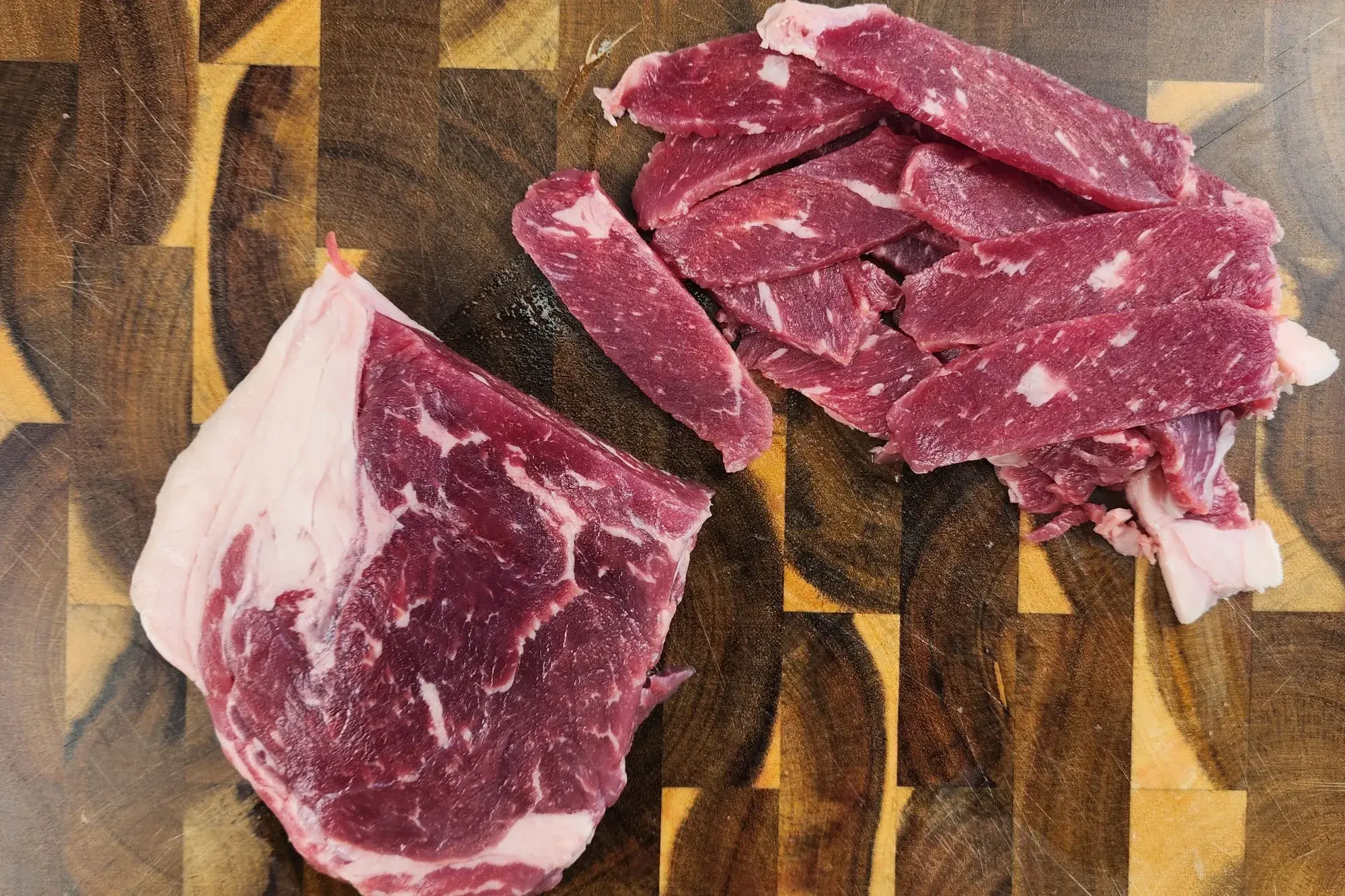 Sliced beef on a wooden board.