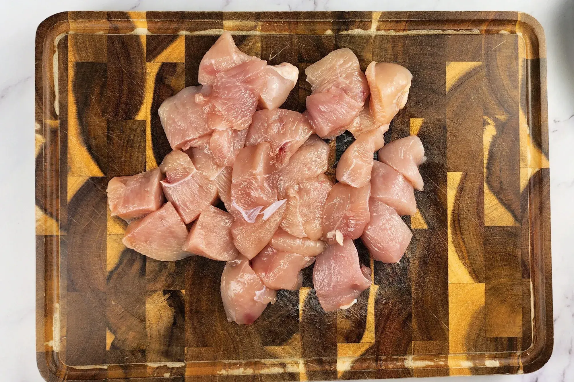 Slices of chicken breast on a wooden chopping board.
