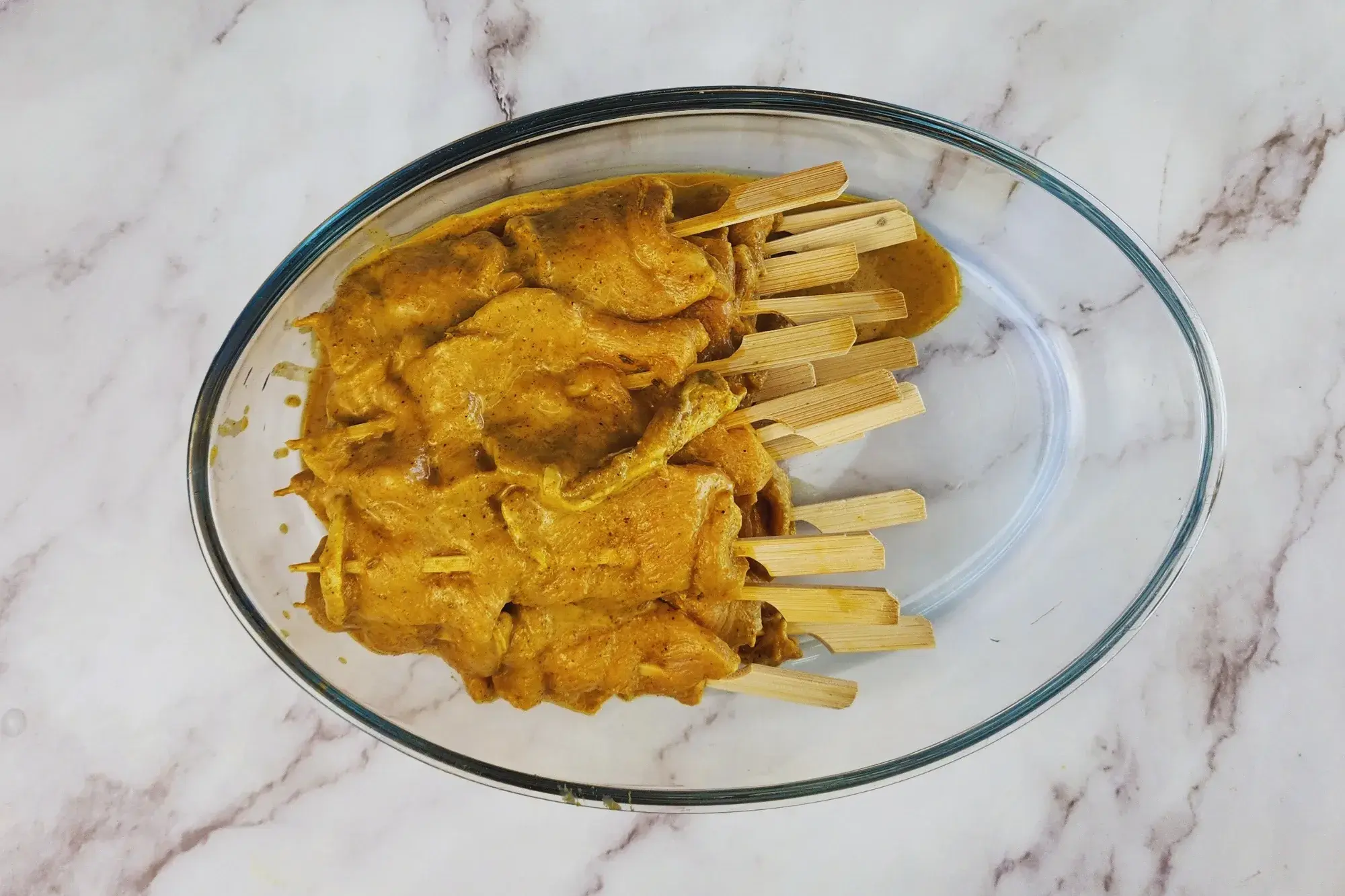 The marinated pork onto skewers.