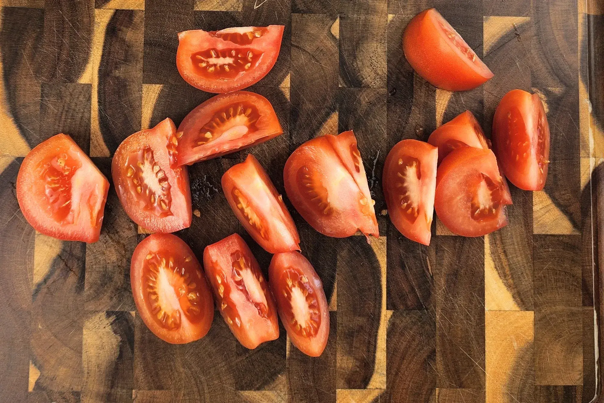 Tomato wedges on a wooden chopping board.